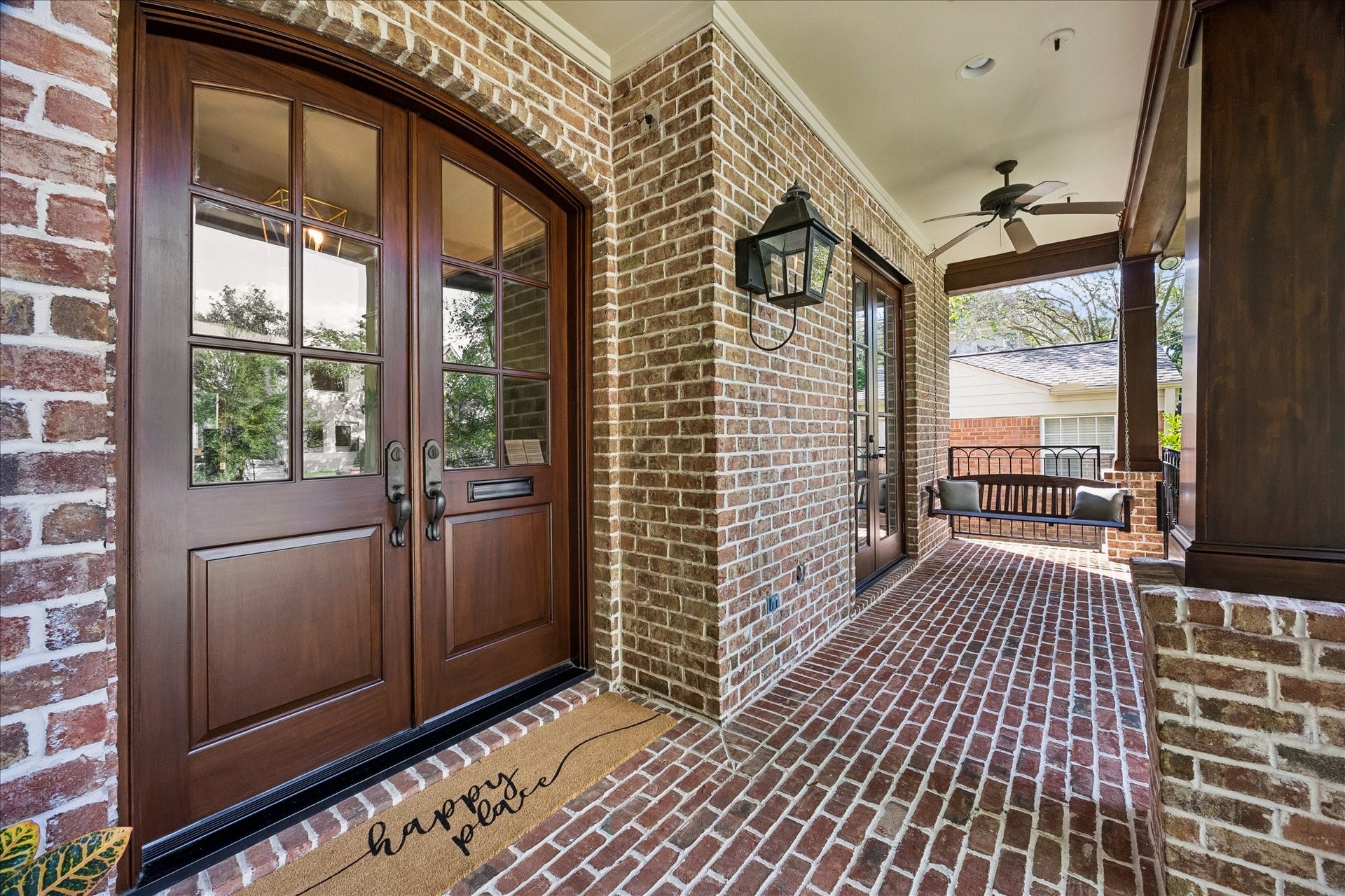 4037 Dumbarton Street, Houston, TX 77025 Charming brick front porch with elegant double doors, a cozy swing, and a ceiling fan, creating a welcoming outdoor retreat.