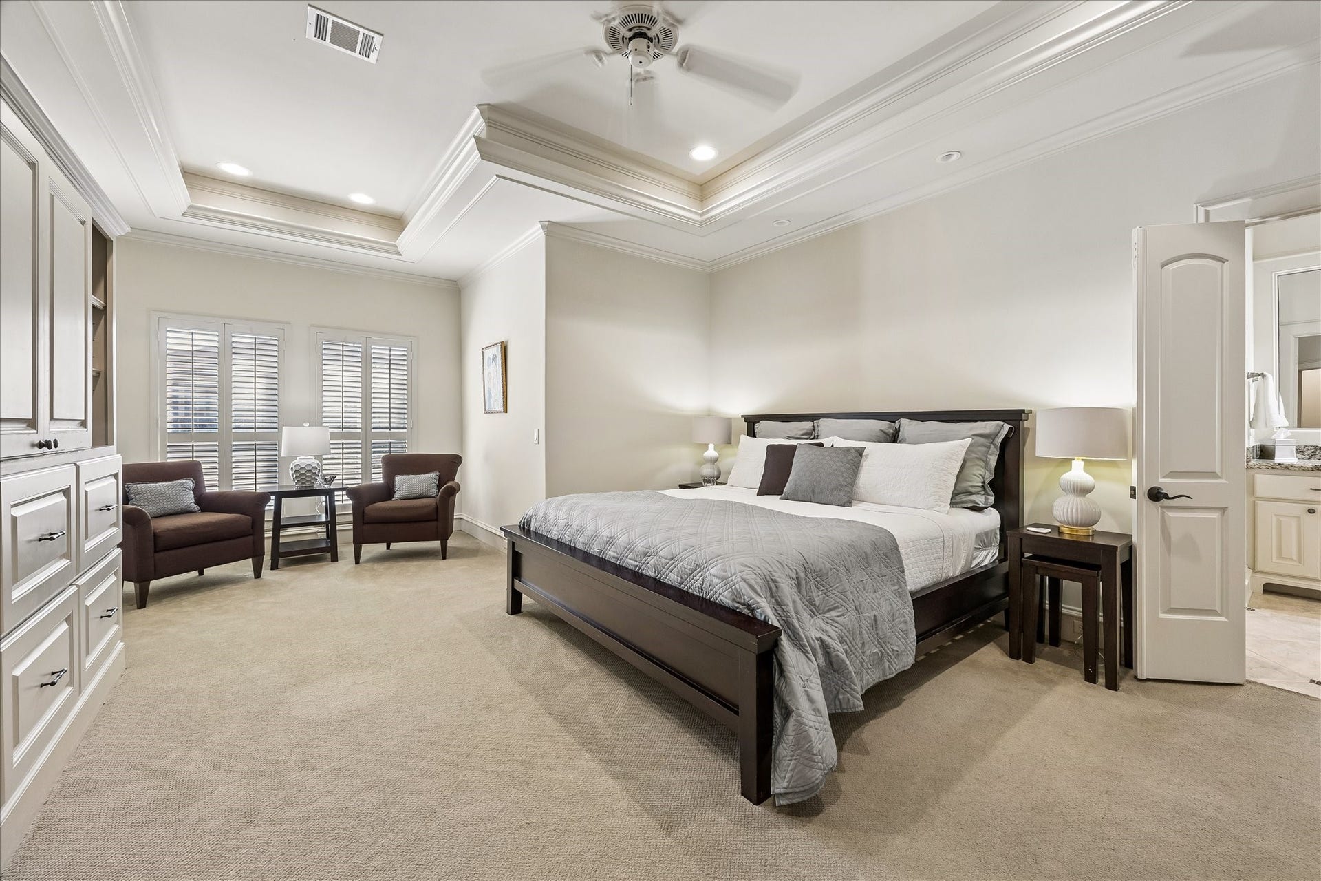 4037 Dumbarton Street, Houston, TX 77025 This spacious primary bedroom with elegant tray ceiling, cozy seating area, and abundant natural light from large windows, offering a serene retreat offers such a restful environment.