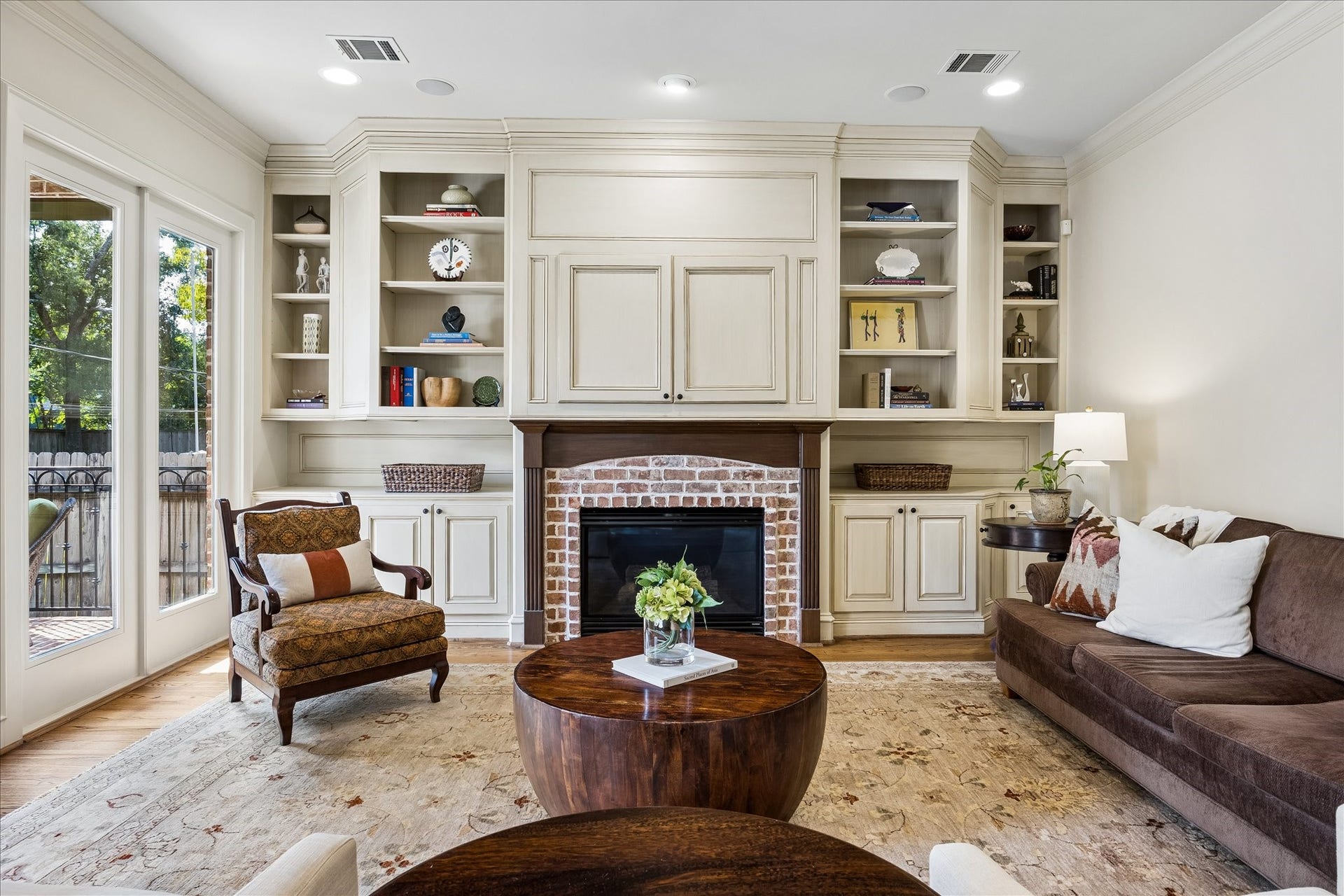 4037 Dumbarton Street, Houston, TX 77025 Beautiful family room features a cozy brick fireplace flanked by custom built-in shelving, all illuminated by natural light from large windows.