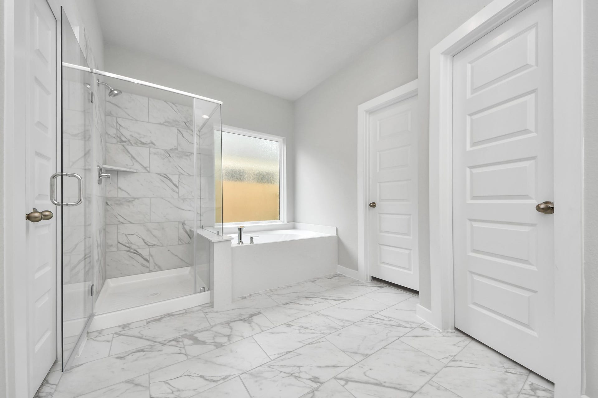 15315 Geranium Field Drive, Houston, TX 77044 Escape to a spa-like oasis in this primary bathroom. Enjoy a walk-in shower with tile surround, a separate garden tub with custom detailing, and an elegant vanity featuring light countertops, modern hardware, and beautiful vanity lights. Experience luxury and relaxation in every detail. Sample photo of completed home with similar floor plan. Actual colors and selections may vary.