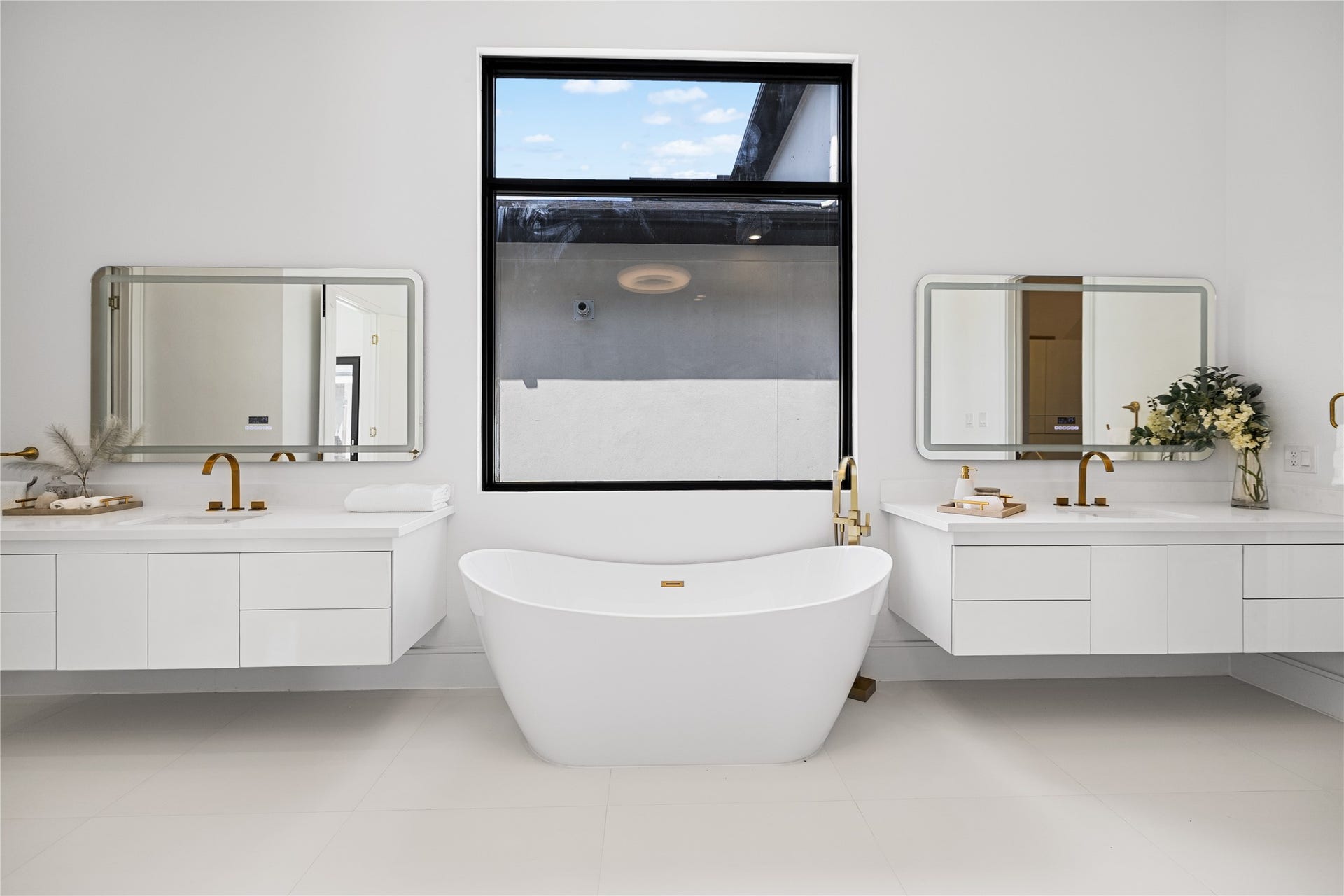 A relaxing soaking tub is beautifully positioned between dual floating vanities, all beneath an impressive ceiling that enhances the baths sense of volume, light, and architectural elegance.