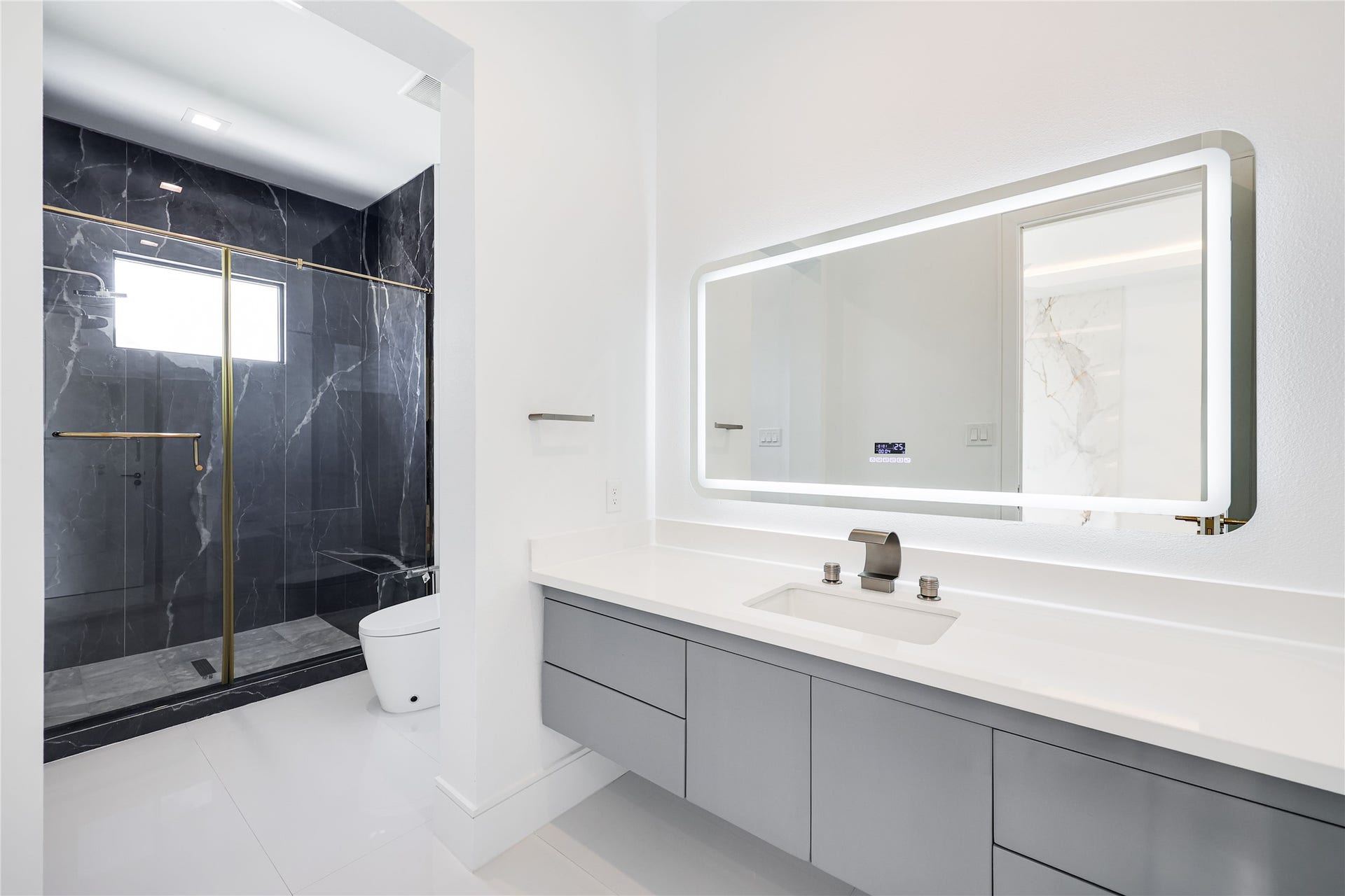 The elegant en-suite bath to this secondary bedroom features a sleek floating vanity and a spacious marble walk-in shower.