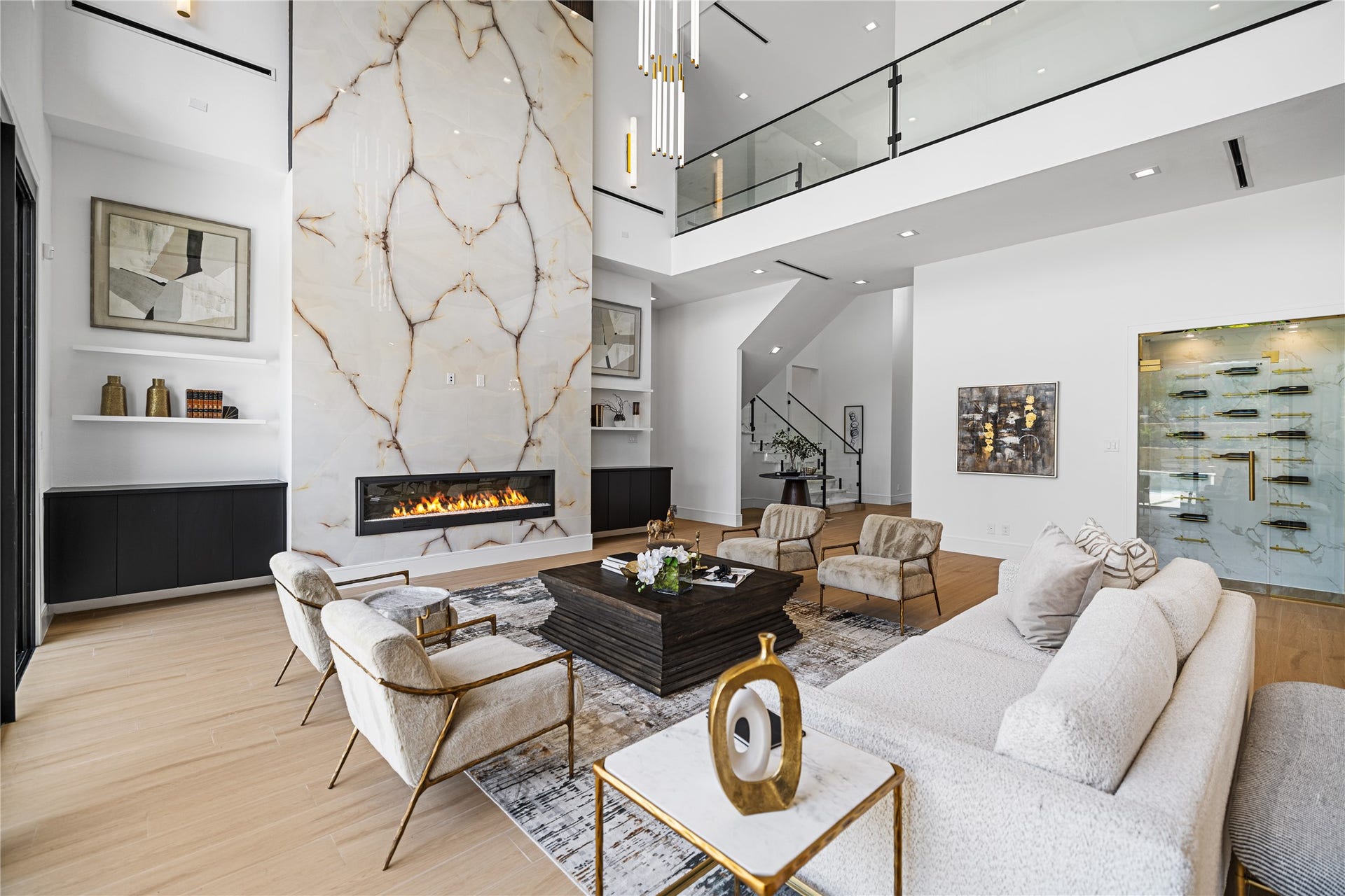 Your two story marble fireplace is flanked by sleek built-ins with open shelving for a curated, gallery-like display in this expansive living space. Just behind the fireplace is a private hallway leading to your first-floor primary suite.