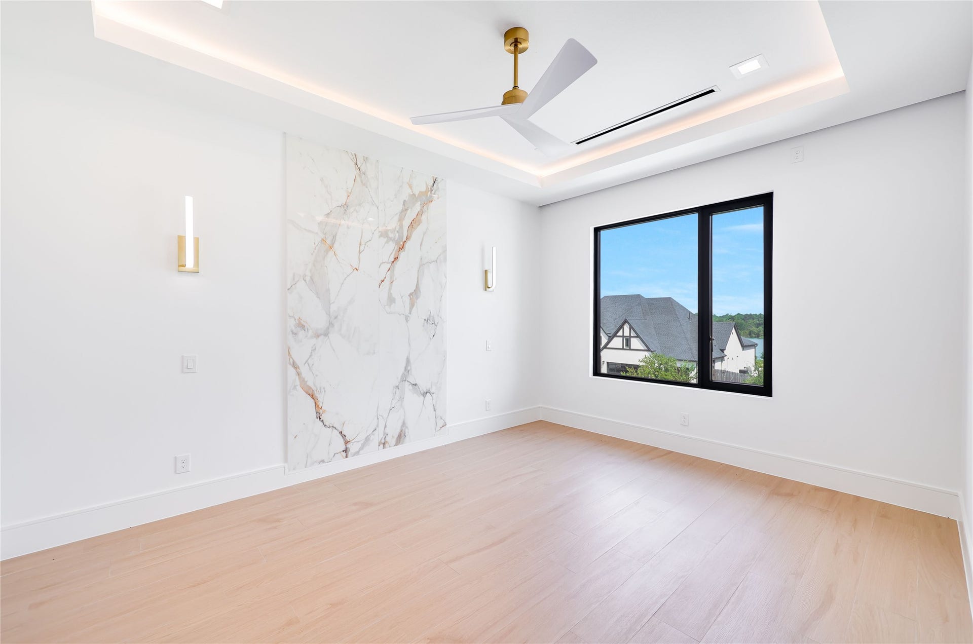 The second of three upstairs en-suite bedrooms, elevated by a custom marble accent wall and sophisticated designer wall sconces for a refined, luxurious finish.