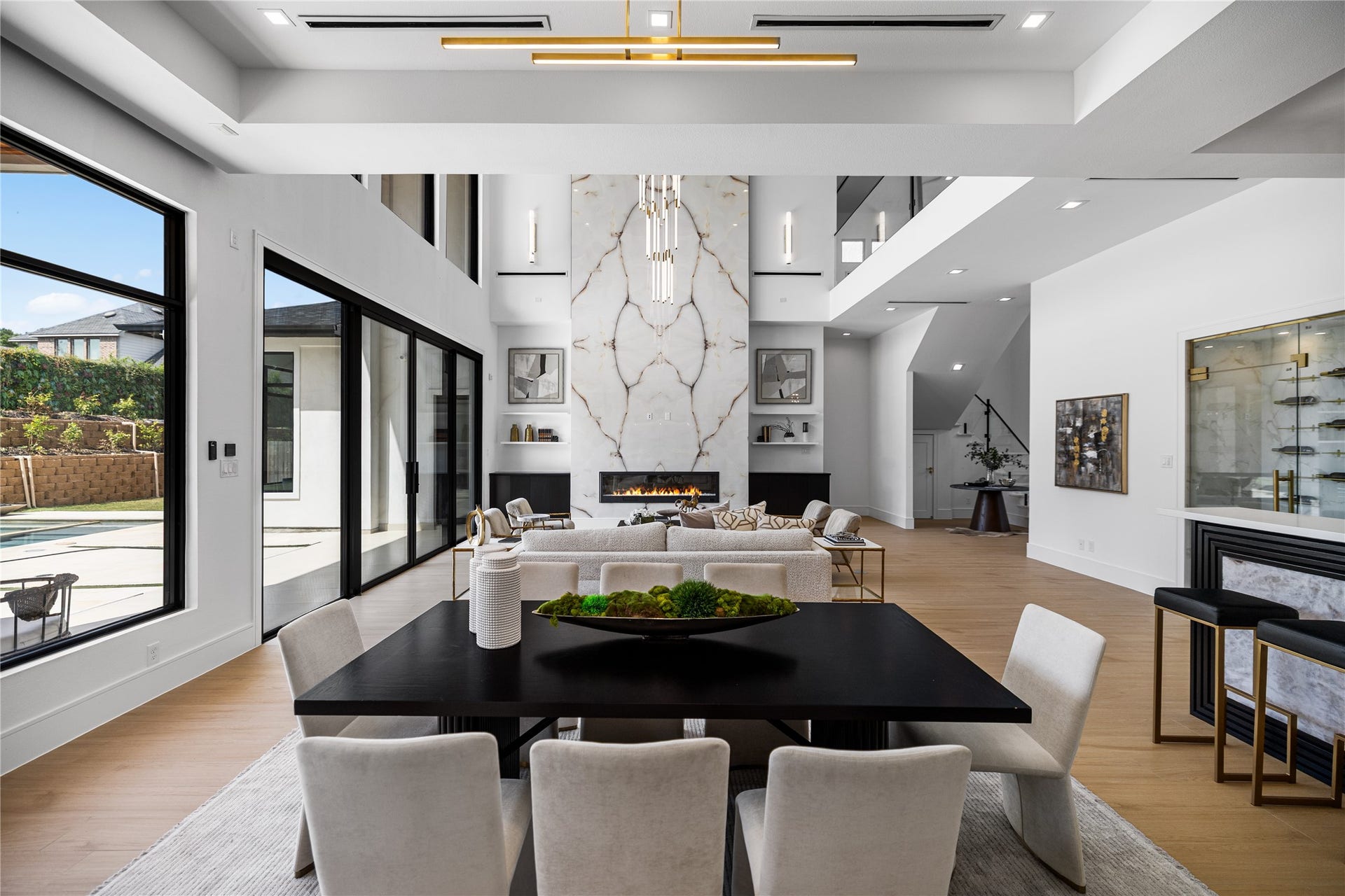 A dining space built for gathering, set beneath a tray ceiling that lends quiet architecture weight to the room. Scaled to hold the largest of tables, it sits in easy view of the marble fireplace wall and pool beyond. This is a room made for long dinners, easy conversations, and memories that follow.