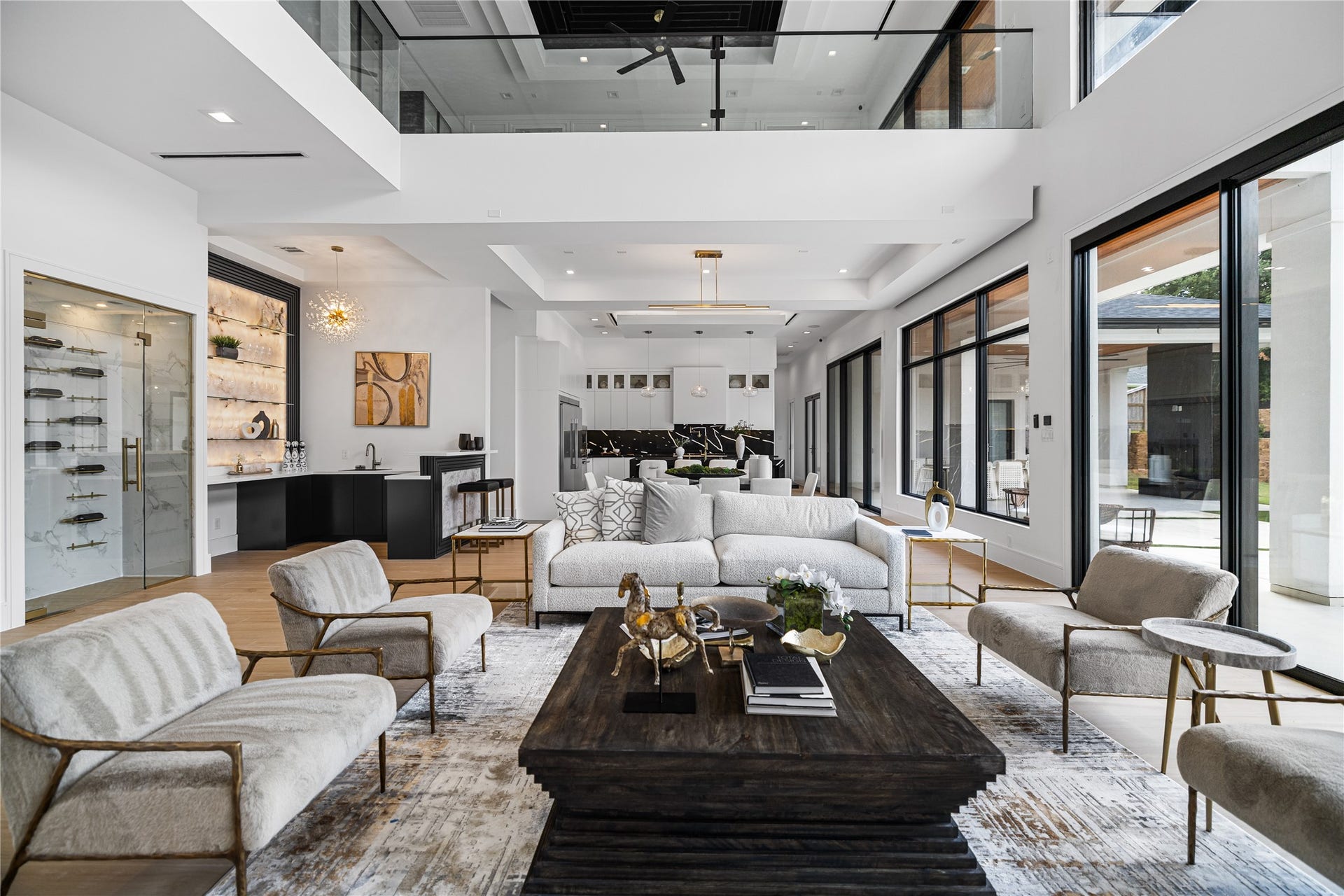 A seamlessly open floor plan flows from the living space into a wine room and ambient-lit bar to the left, while walls of automated sliding glass doors to the right dissolve the boundary between indoors and out.