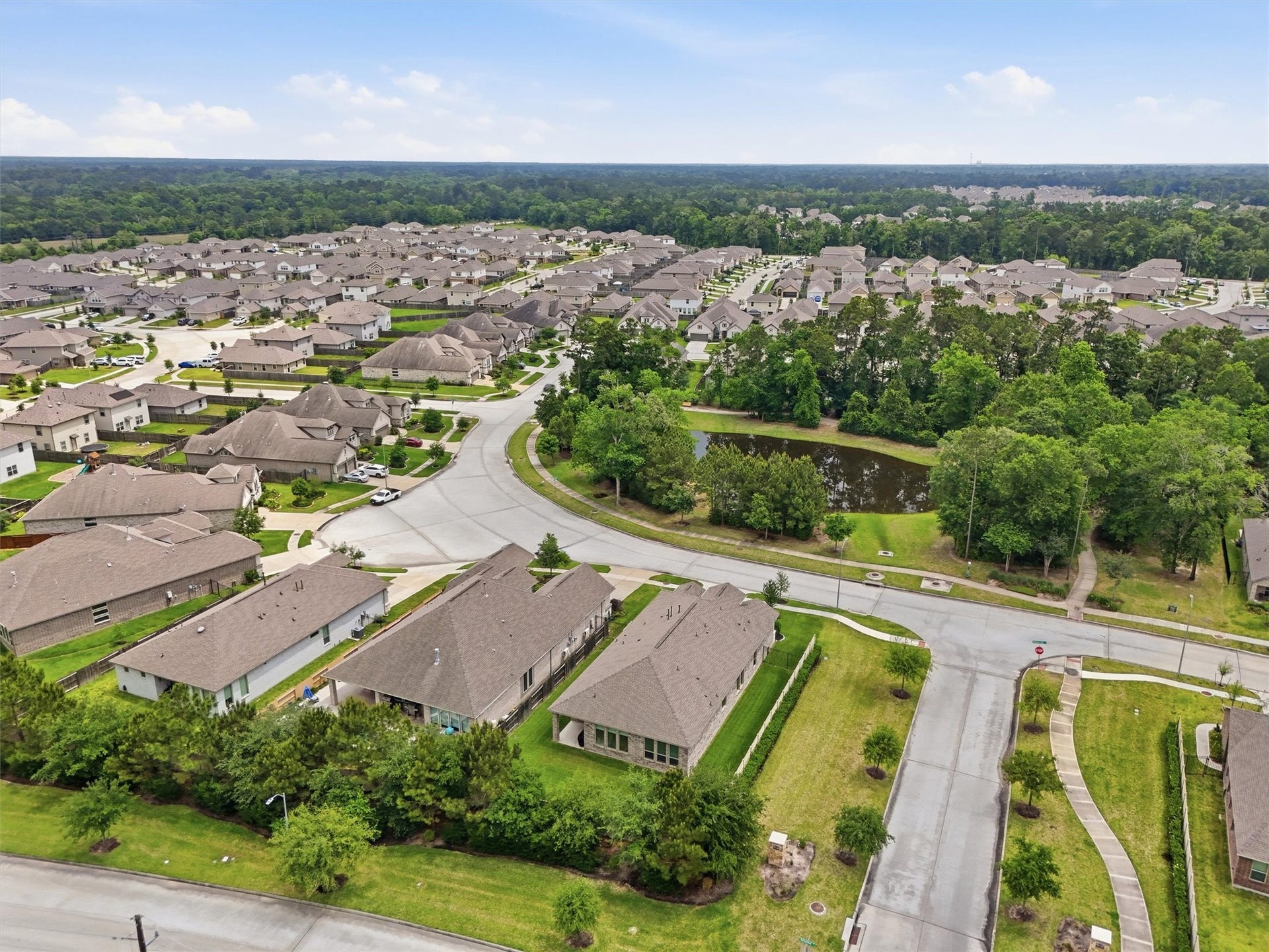 Charming neighborhood with well-maintained homes, winding streets, and a scenic pond surrounded by lush greenery, offering a peaceful suburban setting.