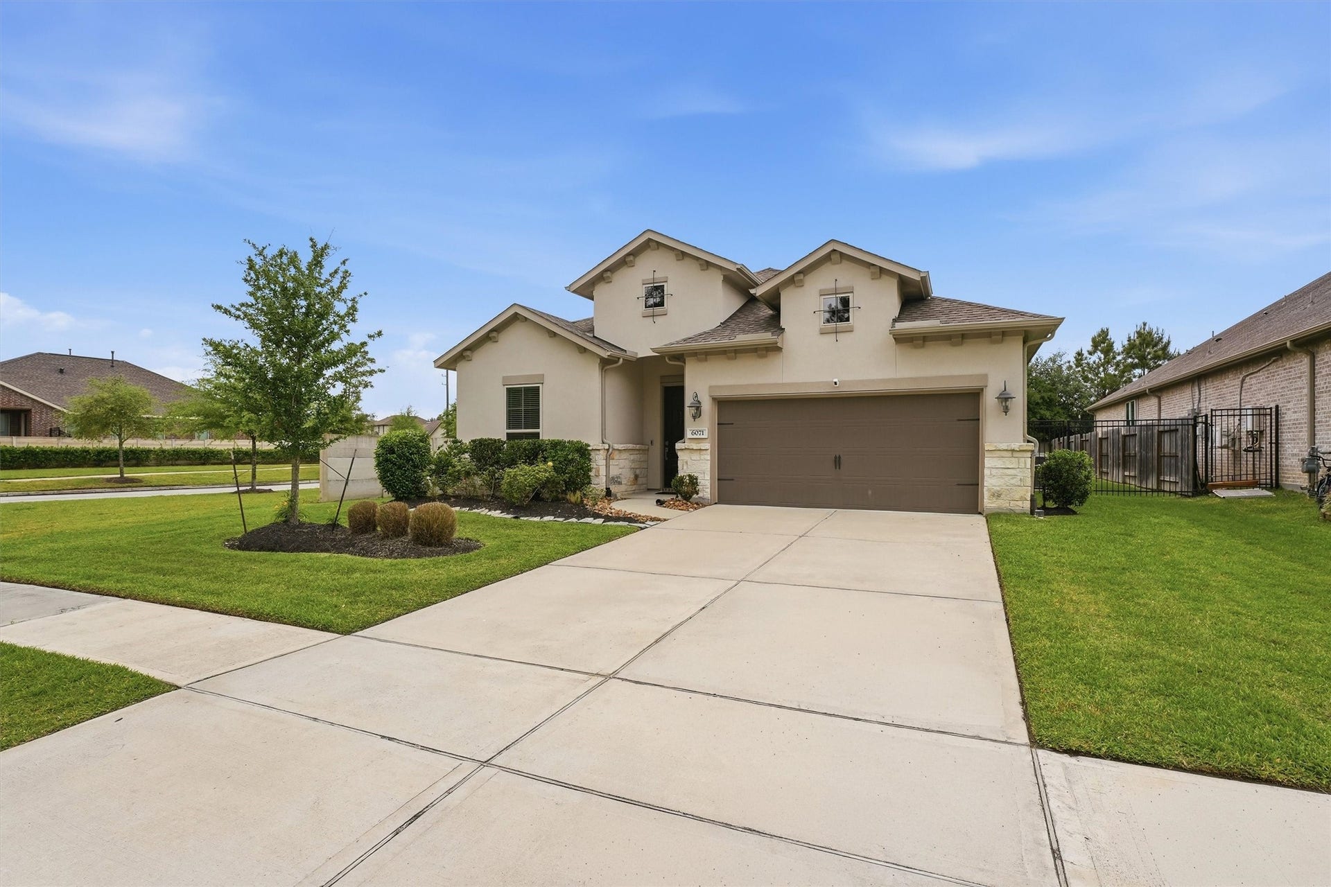 Charming single-story home with a spacious driveway, manicured lawn, and welcoming entrance.