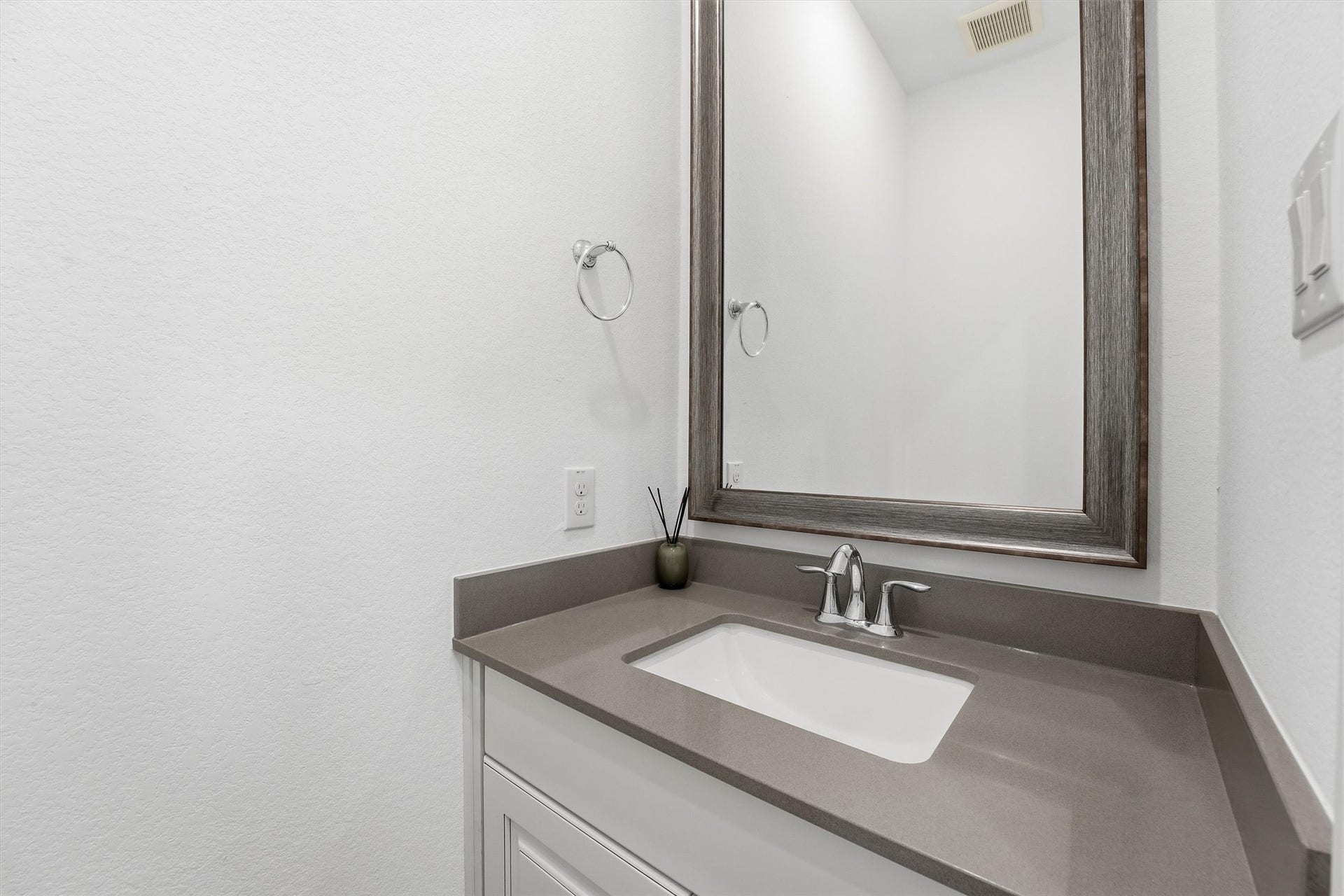 Sleek and modern bathroom featuring a stylish vanity with a solid surface countertop, undermount sink, and a large framed mirror.