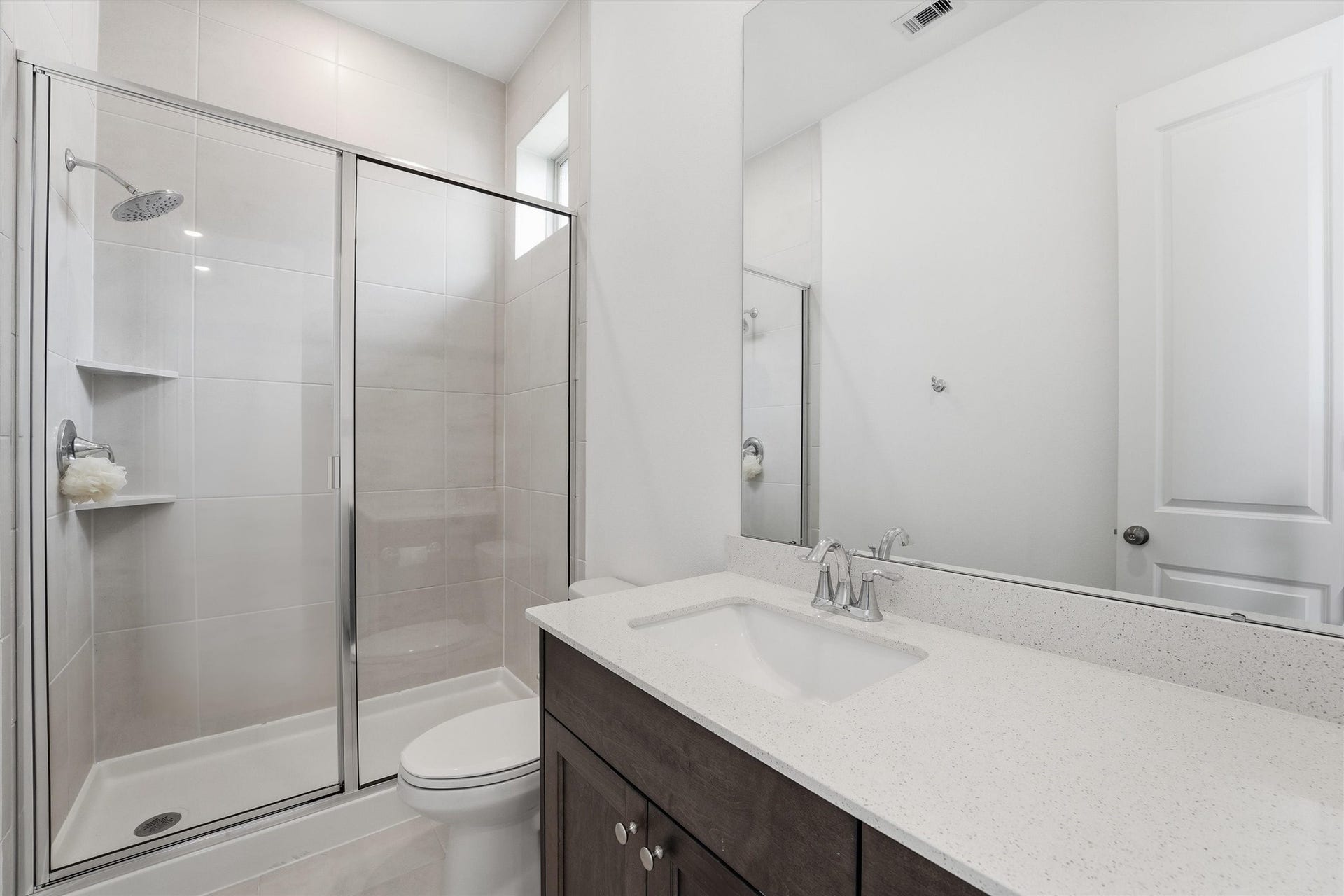 Private Secondary ensuite featuring a sleek glass-enclosed shower, elegant dark wood vanity with a pristine countertop, and ample natural light.