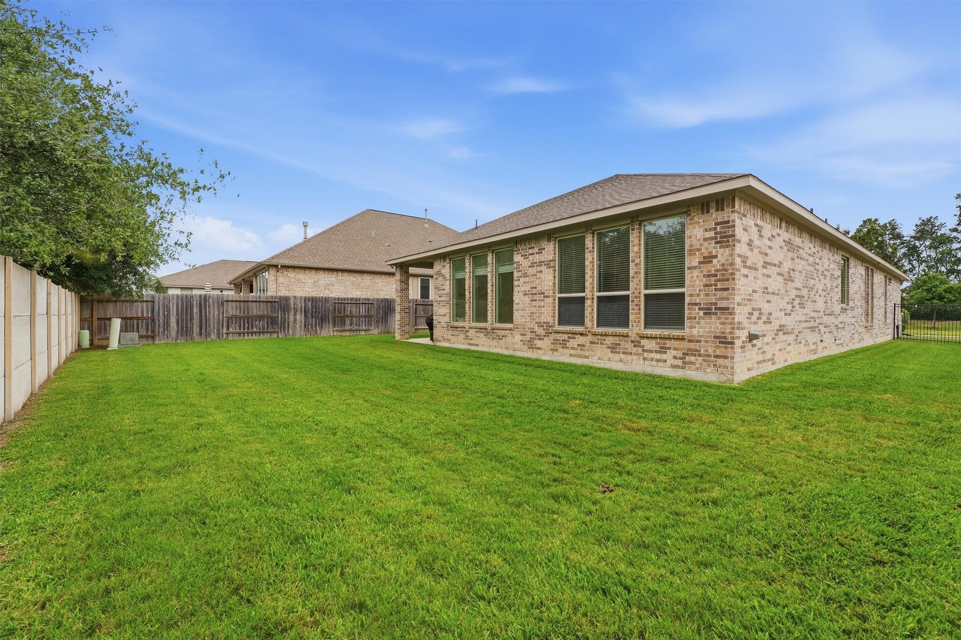 Spacious backyard with lush green lawn and a charming brick exterior, perfect for outdoor activities and relaxation.