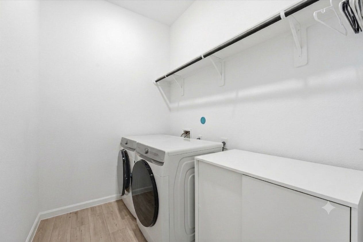 Bright and spacious laundry room featuring modern appliances, ample shelving, and a sleek countertop for convenience.