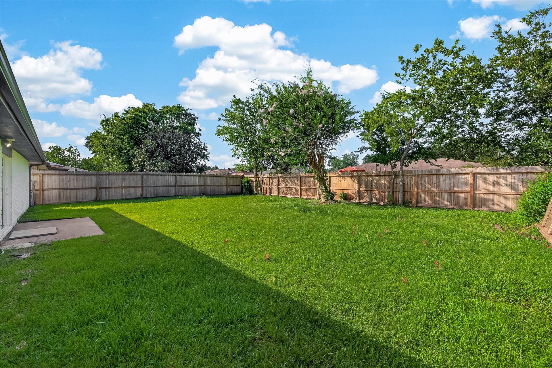 16619 Tibet Road, Friendswood, TX 77546 Spacious backyard with well-maintained grass, bordered by a wooden fence, and featuring mature trees. Ideal for outdoor activities and relaxation.