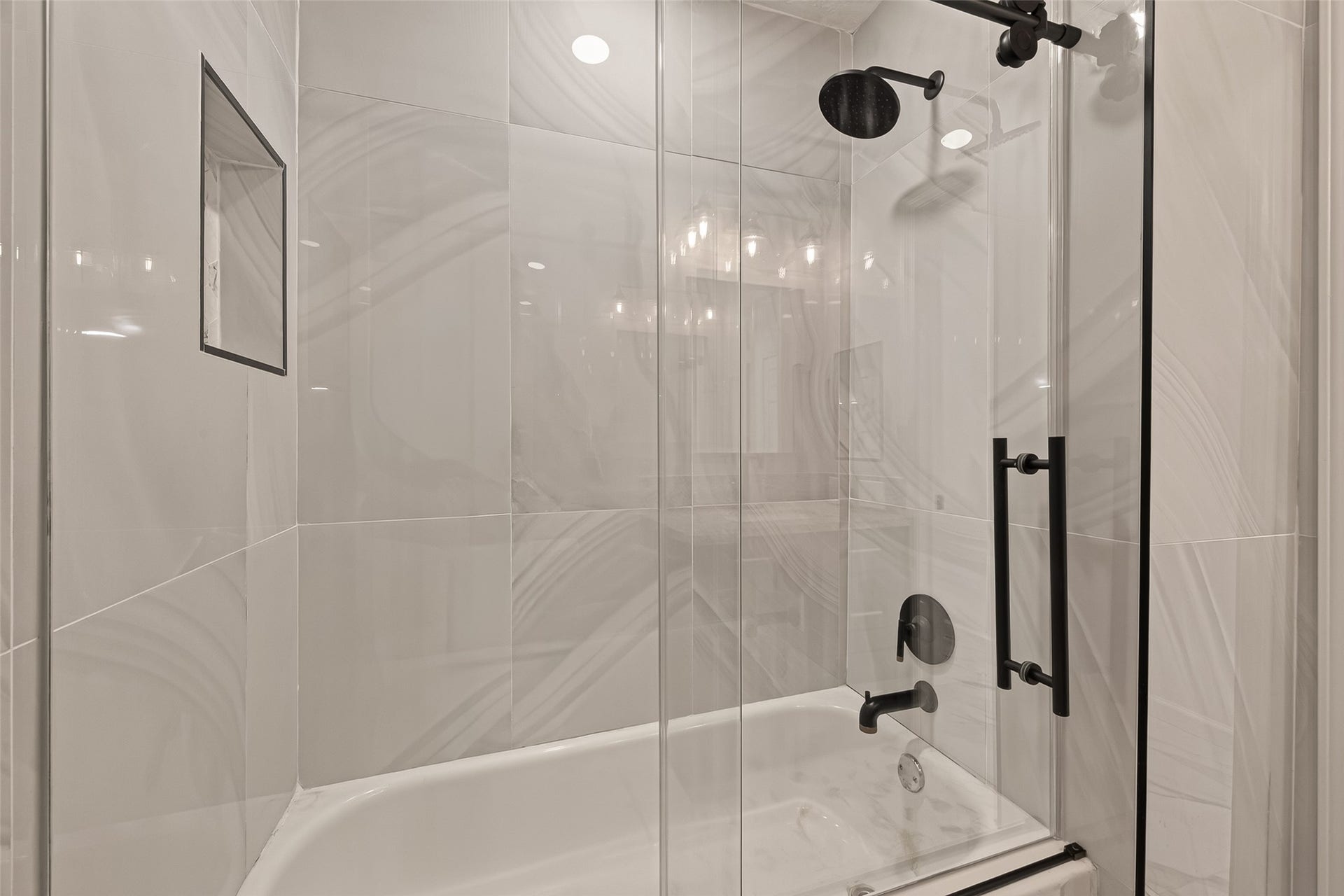 16619 Tibet Road, Friendswood, TX 77546 This bathroom features a modern shower with sleek glass doors, elegant tile walls, and a built-in shelf for convenience. The fixtures are contemporary, adding a stylish touch to the space.