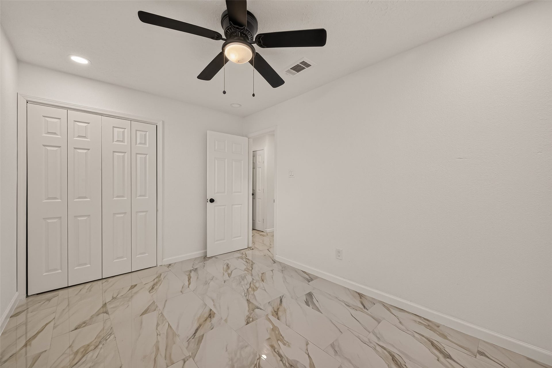 16619 Tibet Road, Friendswood, TX 77546 This room features sleek marble-patterned tile flooring, a ceiling fan, and recessed lighting. It has a white double-door closet and a separate entrance door, all against clean, white walls.