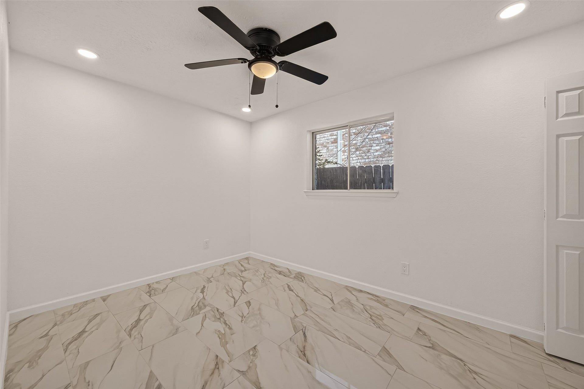16619 Tibet Road, Friendswood, TX 77546 This room features sleek tile flooring, a ceiling fan, and recessed lighting. A window offers natural light, creating a bright and airy space, perfect for a bedroom or office.