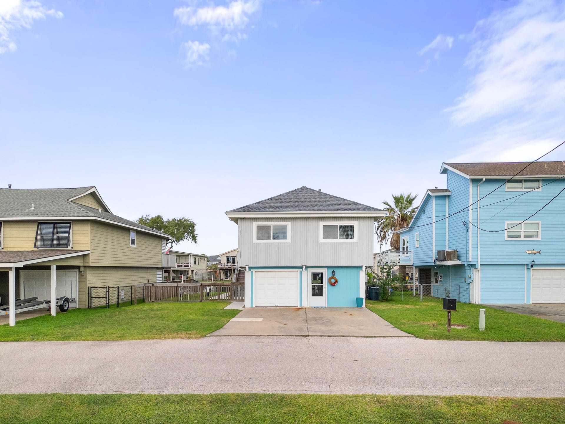 66 Tarpon Street, Bayou Vista, TX 77563 Front exterior view with driveway, attached garage and fenced side yard.