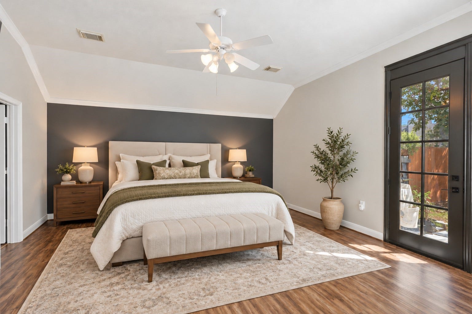 The spacious primary suite features a vaulted ceiling, accent wall, wood-look flooring, and direct outdoor access through a glass-paneled door.**Virtually staged