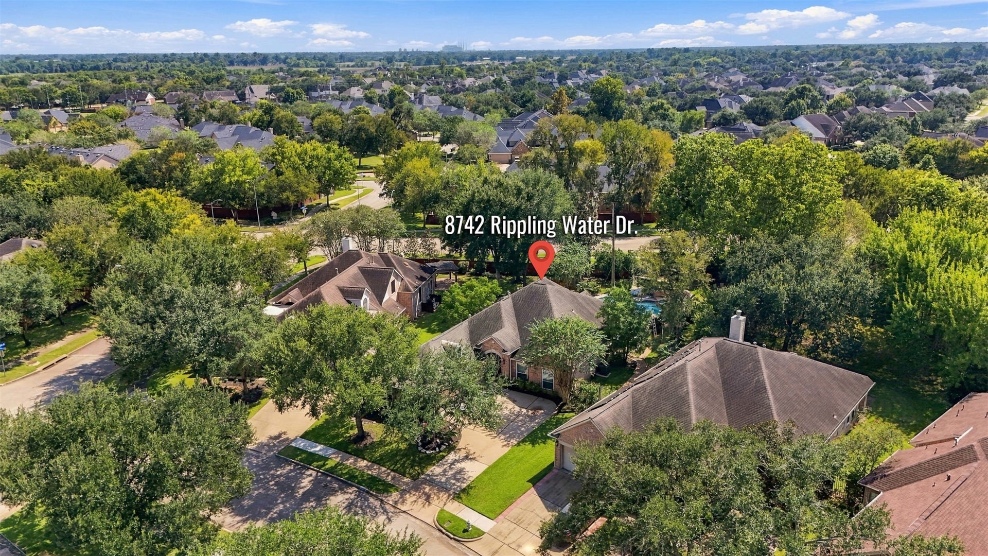 An aerial view places 8742 Rippling Water Drive within the established, tree-lined surroundings of Greatwood and shows the homes setting among neighboring residences.