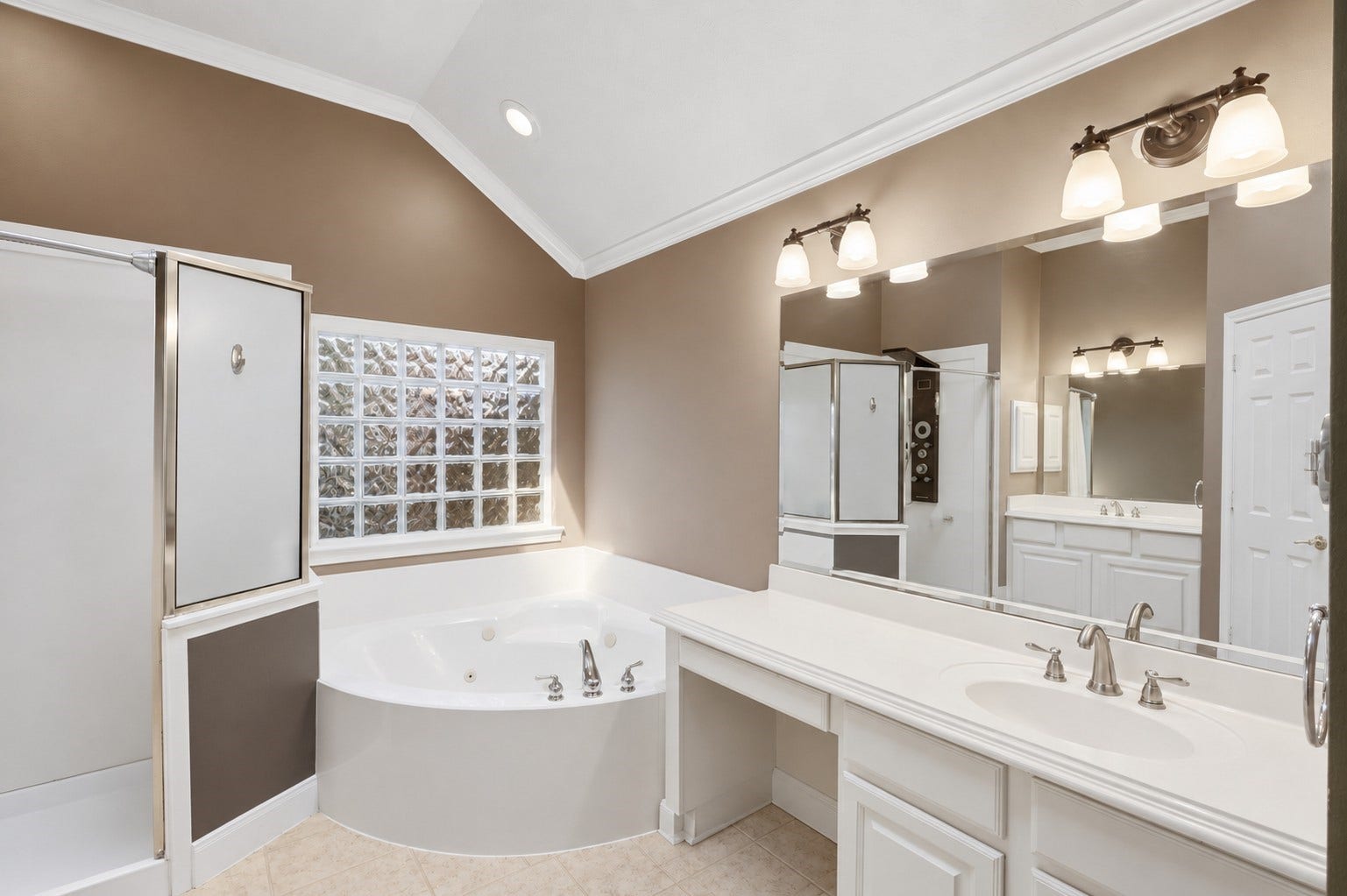 This view showcases the separate shower and tub arrangement, glass-block window, vanity storage, and bright natural light.