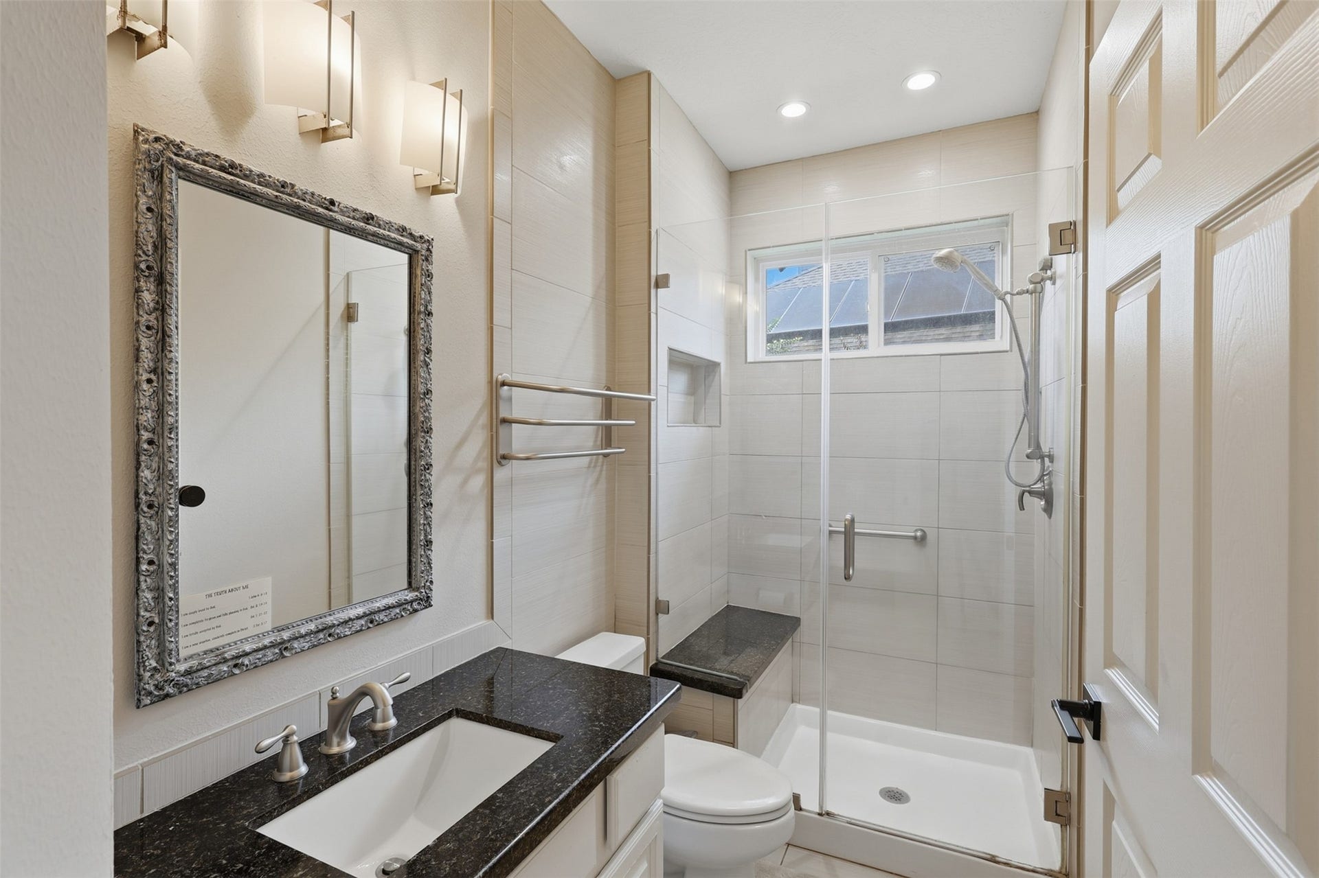 This full bath features a glass-enclosed walk-in shower, built-in bench, tiled surround, and a granite-topped vanity.