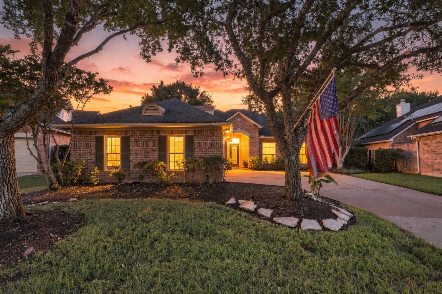 Warm evening lighting creates an inviting view of the homes front elevation and covered entry.