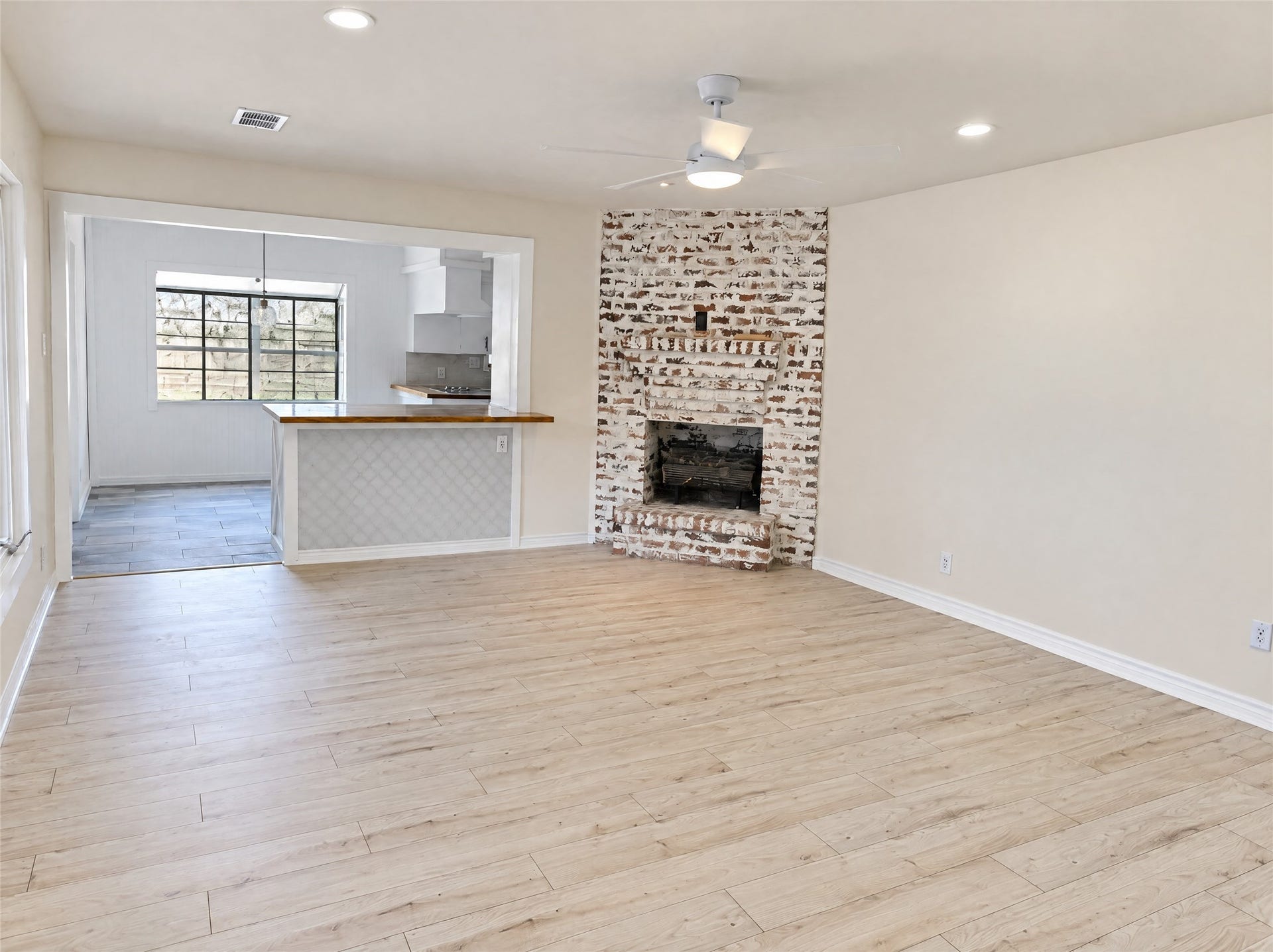 16411 Amcreek Road, Houston, TX 77068 Flowing effortlessly toward the kitchen, the primary living space showcases a whitewashed brick fireplace as its centerpiece. Recessed lighting, a modern ceiling fan, and direct sightlines to the breakfast bar create a warm, connected atmosphere for gathering with family and friends.