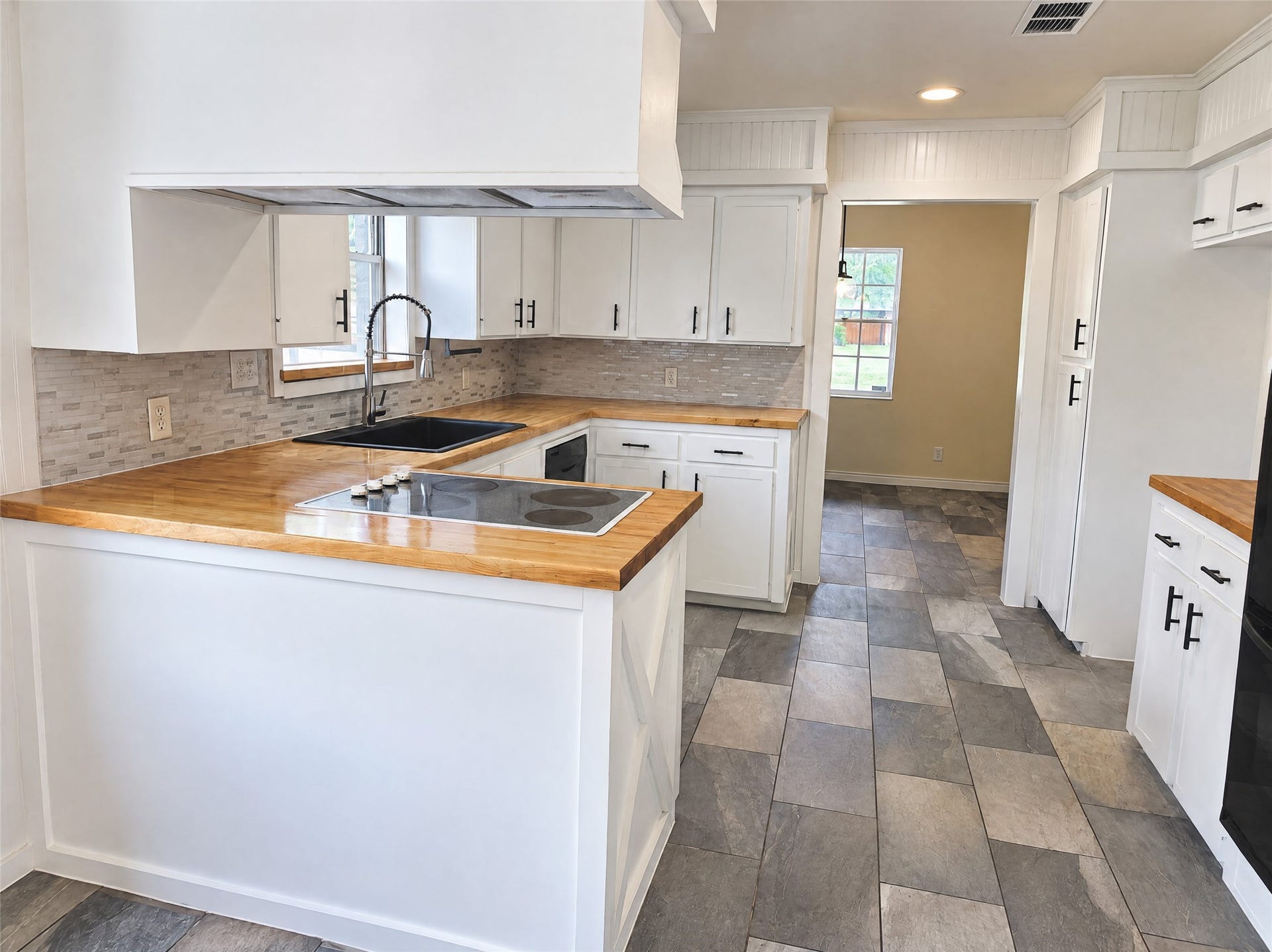 16411 Amcreek Road, Houston, TX 77068 Complete with an integrated cooktop, undermount black composite sink, stainless gooseneck faucet, dishwasher, and charming beadboard detailing, meal prep is an absolute pleasure.