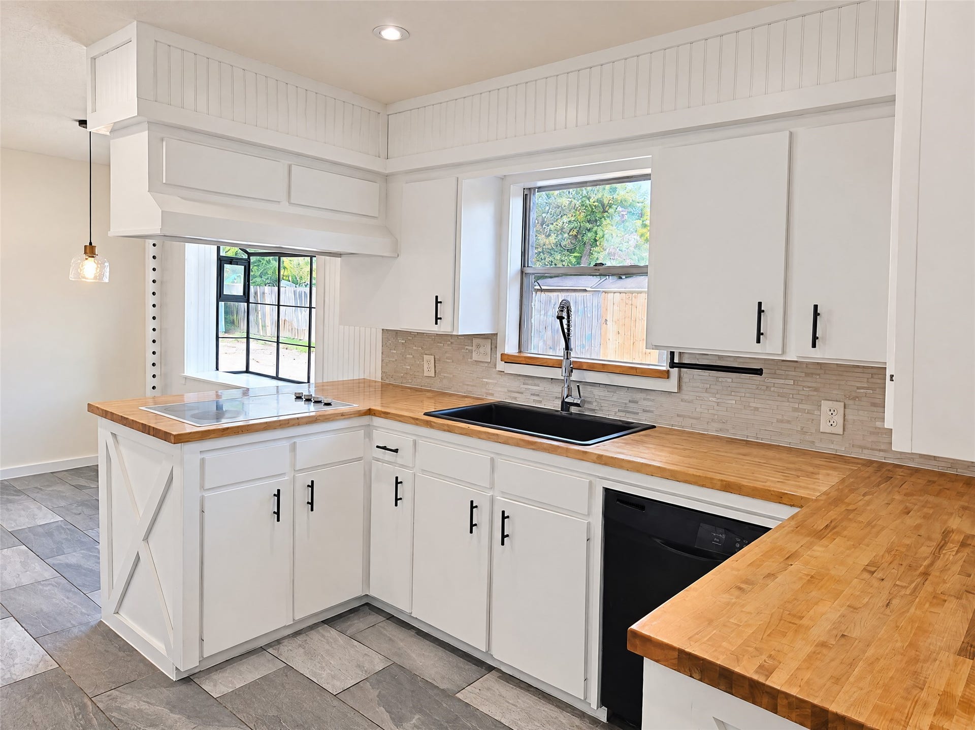 16411 Amcreek Road, Houston, TX 77068 Crisp white cabinetry with modern matte black pulls pairs beautifully with solid butcher block counters and a textured tile backsplash.