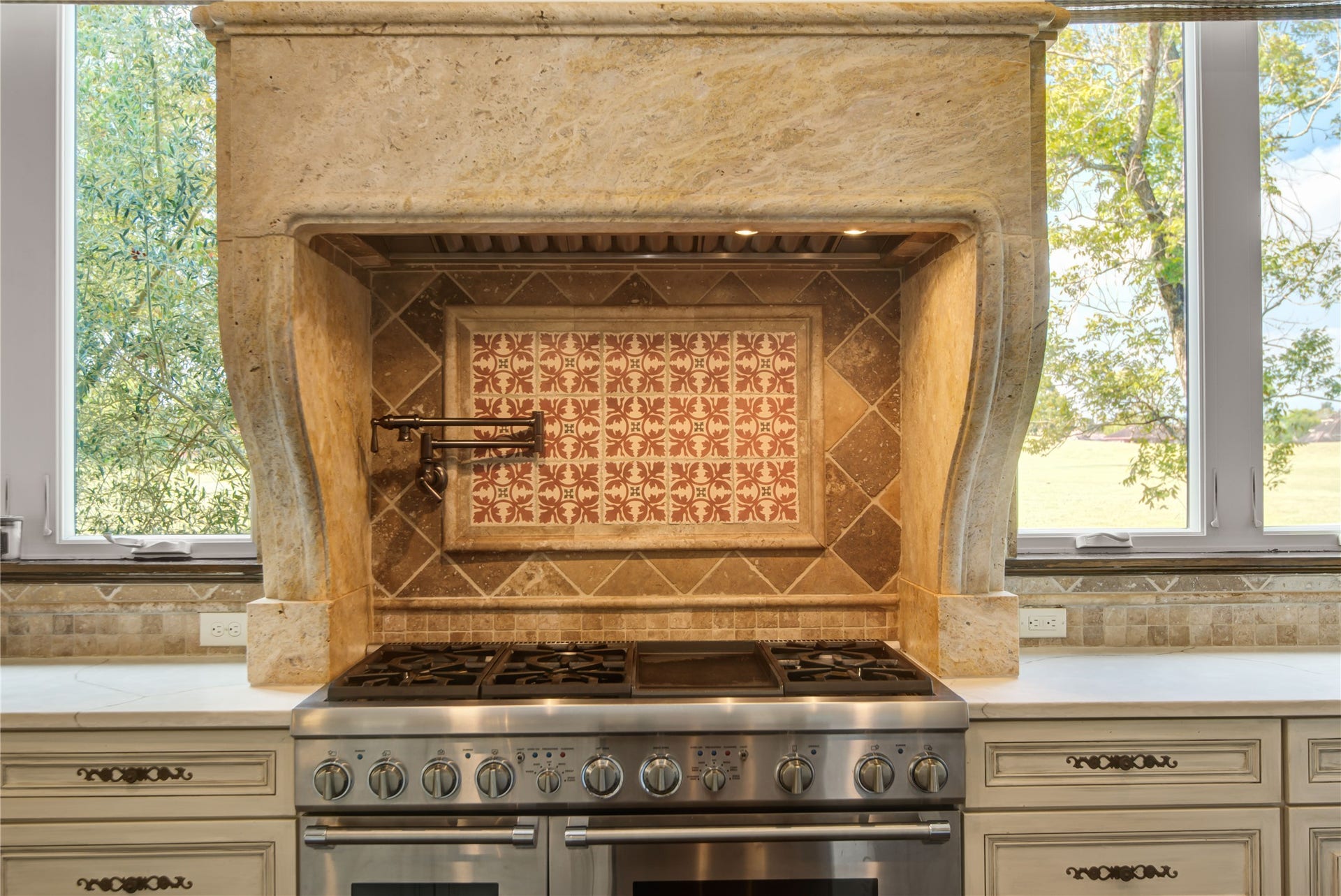 10 Sullivans Lane, Missouri City, TX 77459 This kitchen features a high-end Thermador stainless steel gas stove with intricate tile backsplash and a stone hood. This inviting cooking space also features custom pot filler