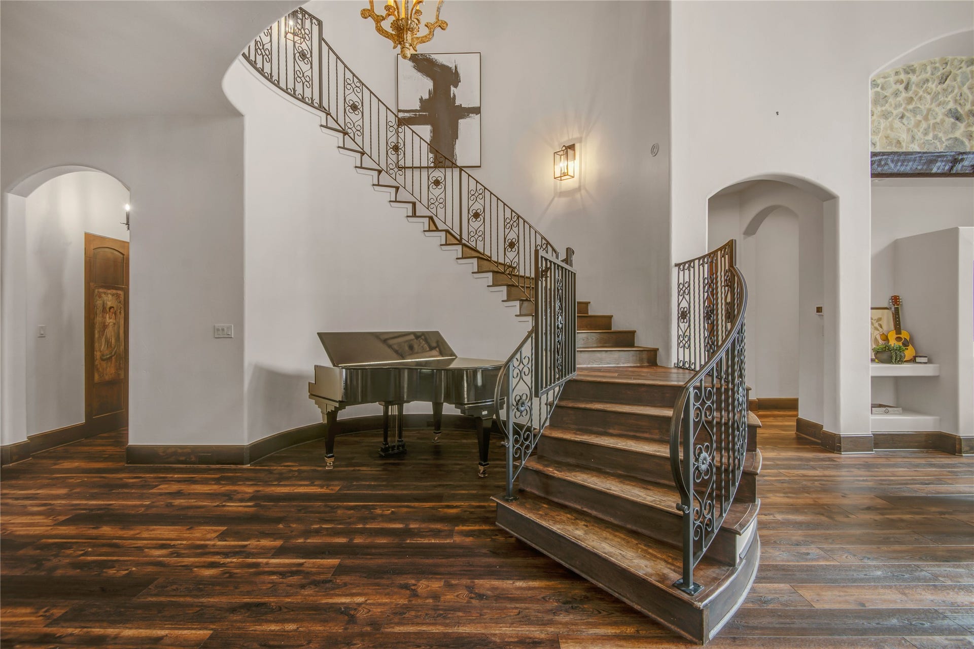 10 Sullivans Lane, Missouri City, TX 77459 Elegant and spacious entryway features a sweeping staircase as a focal point. Beautiful staircase of wooden stairs and custom wrought-iron railings that curve gracefully as they ascend. A wall sconce provides soft, ambient lighting. The chandelier above the staircase contributes to the upscale, classic aesthetic of the space.