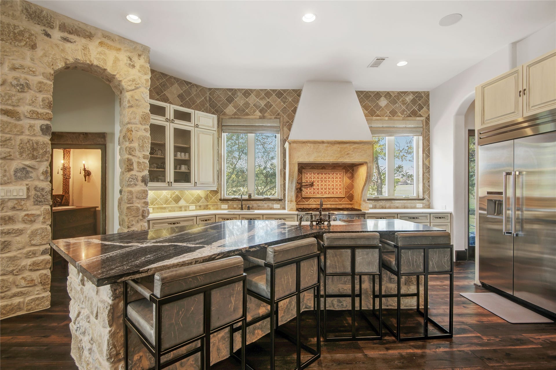 10 Sullivans Lane, Missouri City, TX 77459 Kitchen is accented by a unique range hood and decorative tile backsplash, offering a blend of traditional charm and modern luxury.