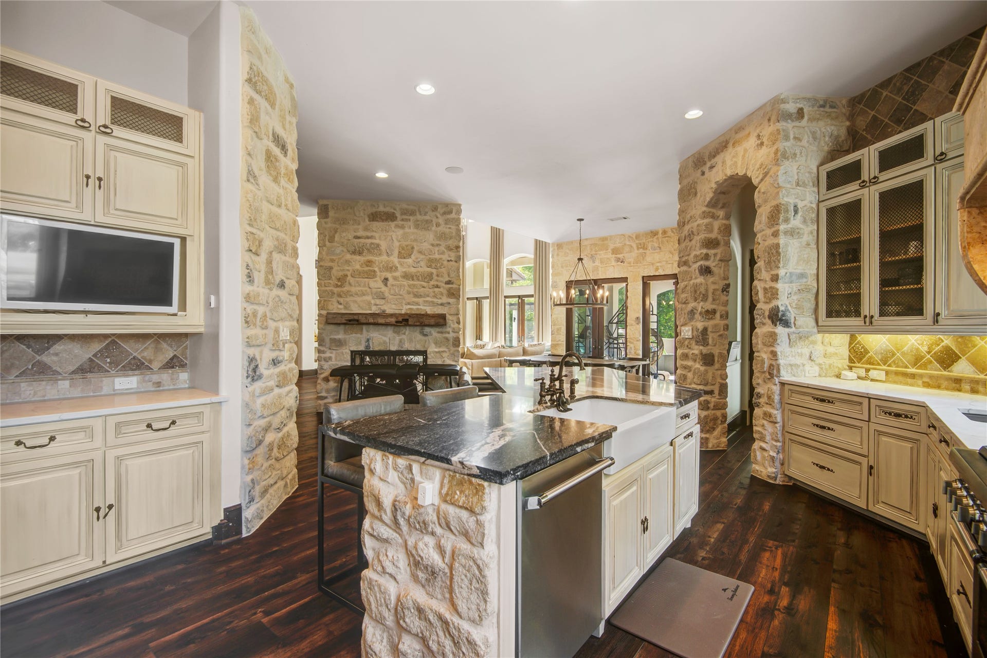 10 Sullivans Lane, Missouri City, TX 77459 The elegant stone walls and rustic wood floors are complemented by cream cabinetry and a large center island with a modern sink. The space is brightened by ample natural light and has an open flow to the dining area.