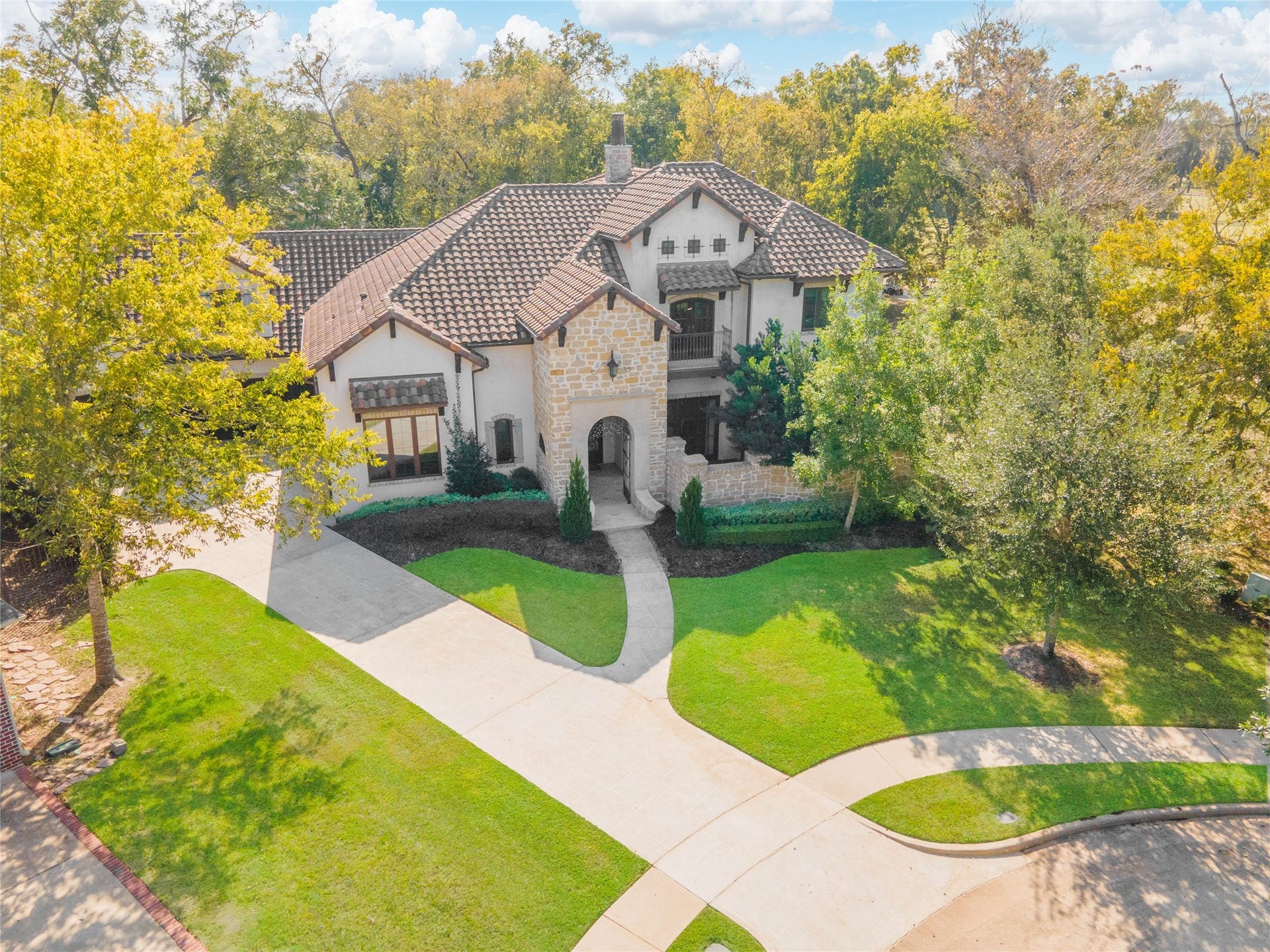 10 Sullivans Lane, Missouri City, TX 77459 Impressive curb appeal with its timeless stone-and-stucco exterior, elegant rooflines, and beautifully detailed windows. Nestled on a large, meticulously landscaped lot featuring a sweeping curved driveway, mature trees, and a serene, private setting. The lush greenery frames the residence perfectly, creating a grand first impression and showcasing the luxury and craftsmanship found throughout the home. Ideal for those seeking both sophistication and tranquility, this home stands out as a true showpiece