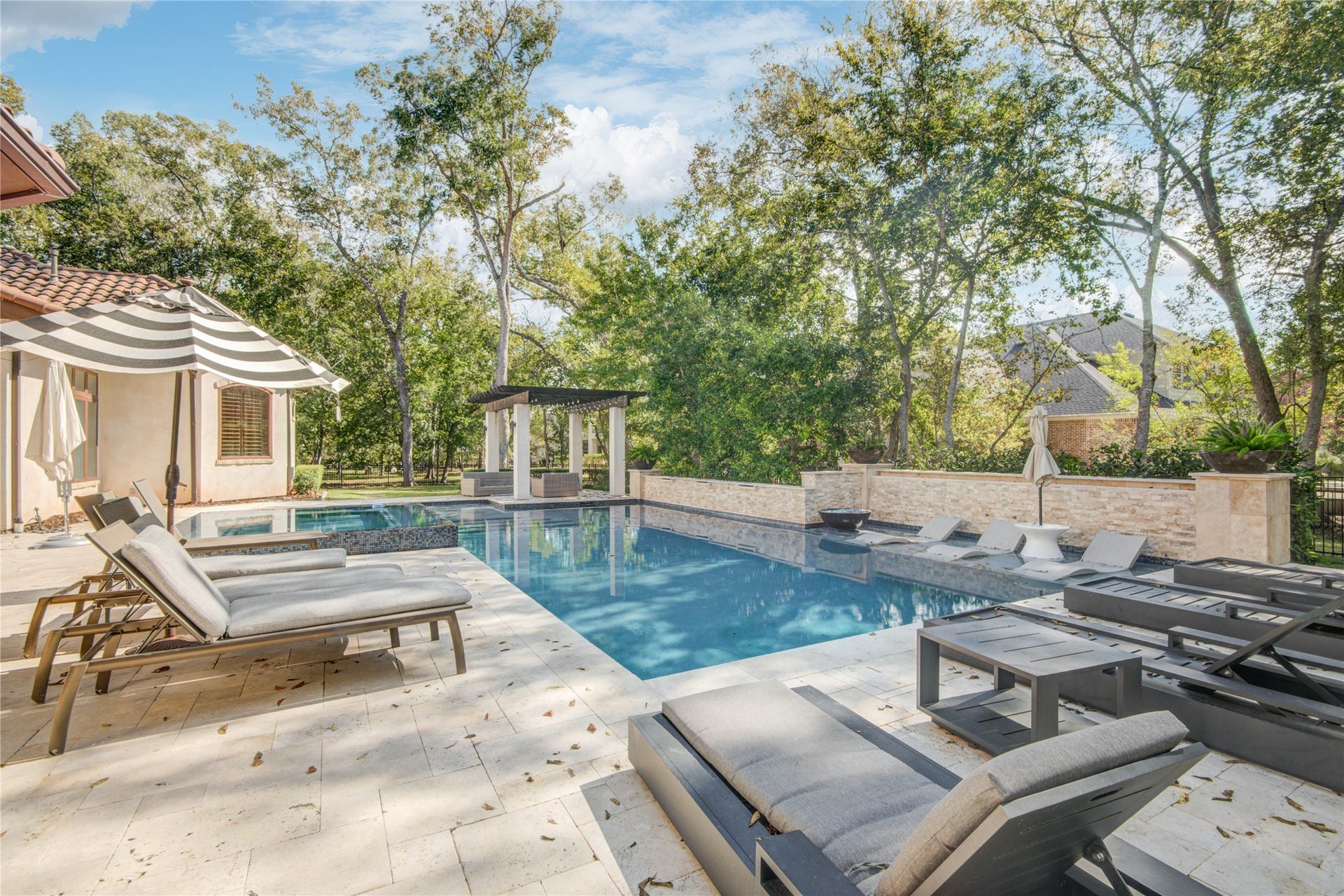 10 Sullivans Lane, Missouri City, TX 77459 Inviting pool area is beautifully landscaped with mature trees providing privacy and shade, and there's an elegant pergola for added charm and shelter. Perfect for outdoor entertaining or serene retreat.