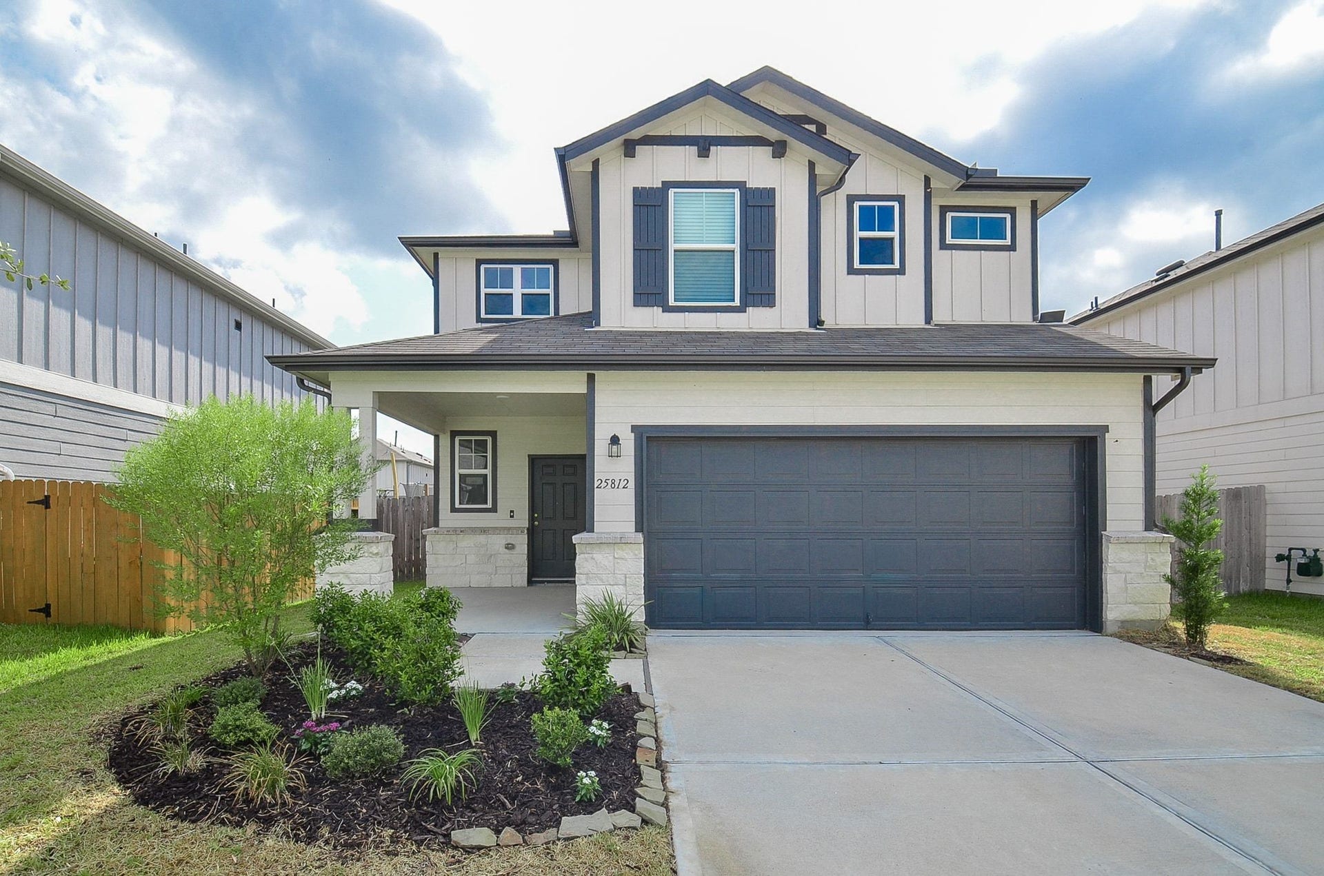 Charming two-story home with a modern facade, featuring a spacious two-car garage and a welcoming front porch, surrounded by well-maintained landscaping.