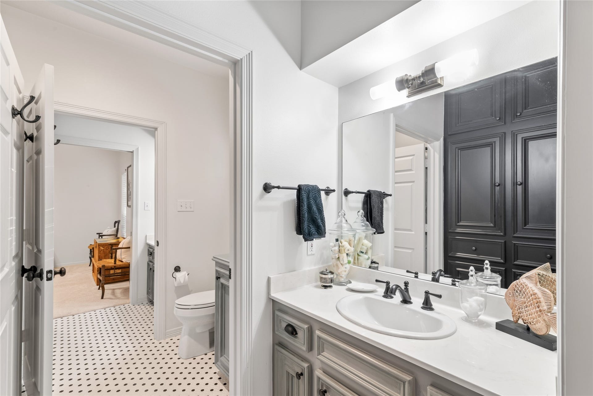 901 Longmire Road, #51, Conroe, TX 77304 Elegant bathroom with classic black and white tile flooring, a spacious vanity with dark fixtures, and ample cabinetry for storage.