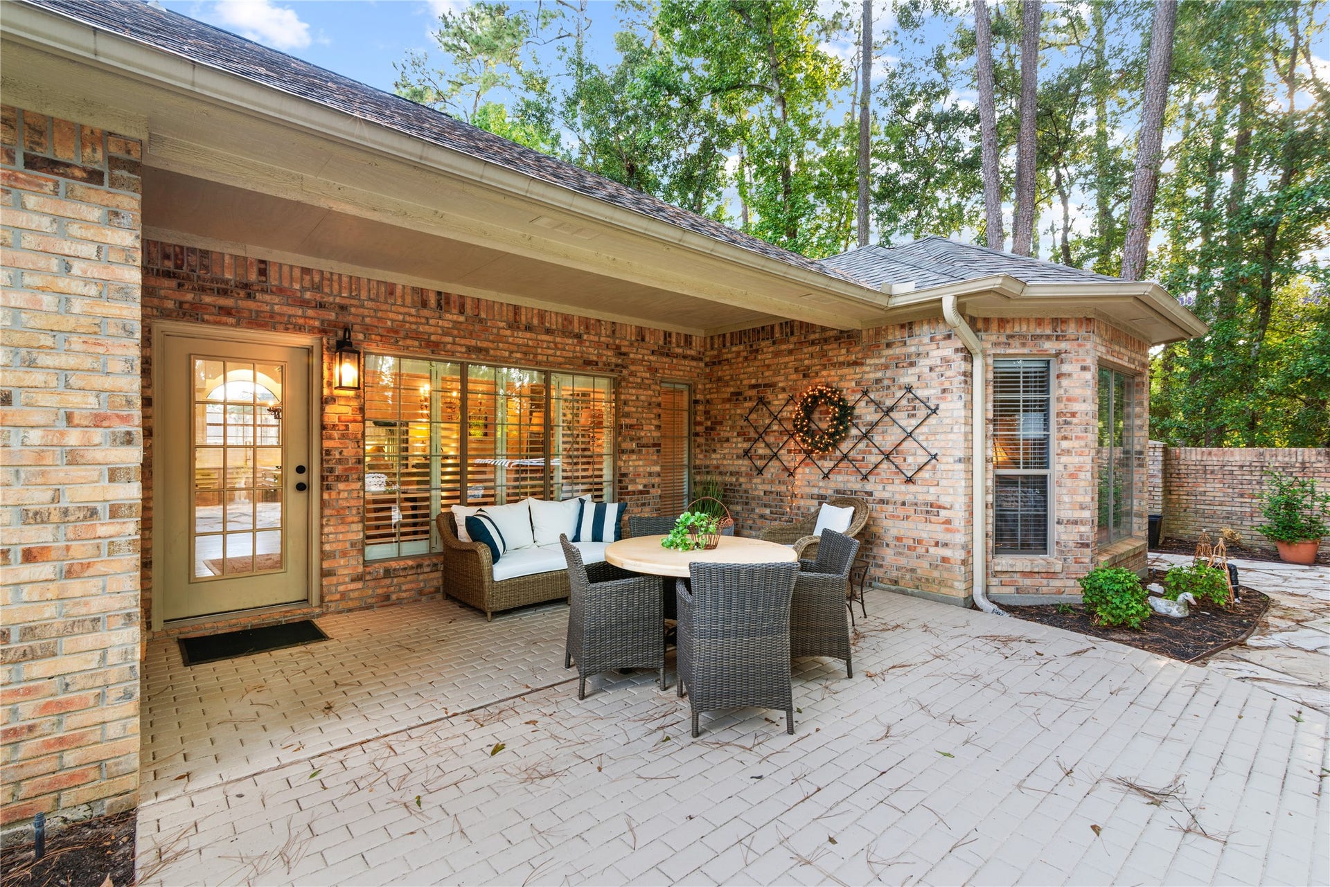 901 Longmire Road, #51, Conroe, TX 77304 Spacious private brick patio with cozy seating area and dining set, surrounded by lush greenery for a tranquil outdoor retreat.