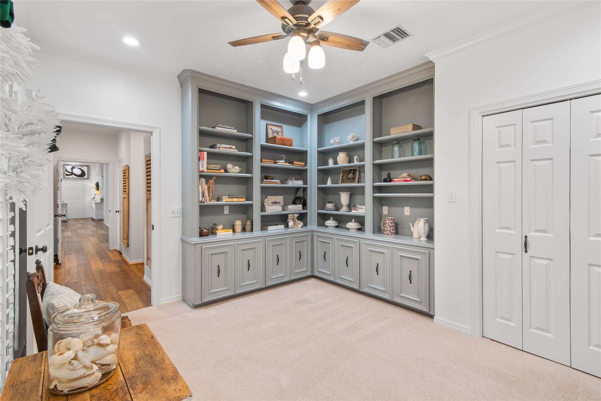 901 Longmire Road, #51, Conroe, TX 77304 Built-in shelving, perfect for display and storage, complemented by soft carpeting and a ceiling fan for comfort.