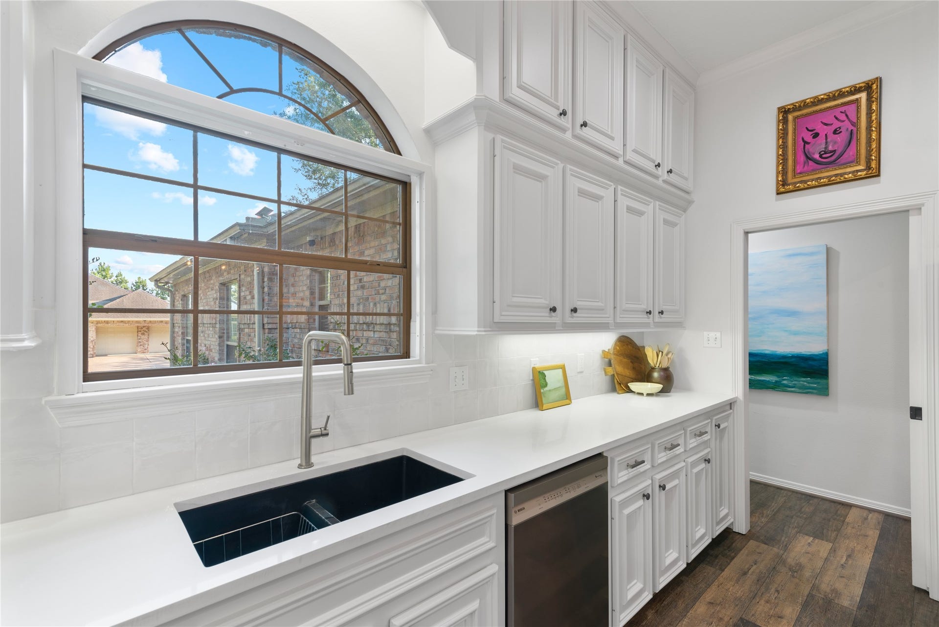 901 Longmire Road, #51, Conroe, TX 77304 Bright kitchen with elegant white cabinetry, a sleek black sink, and a large arched window offering plenty of natural light.