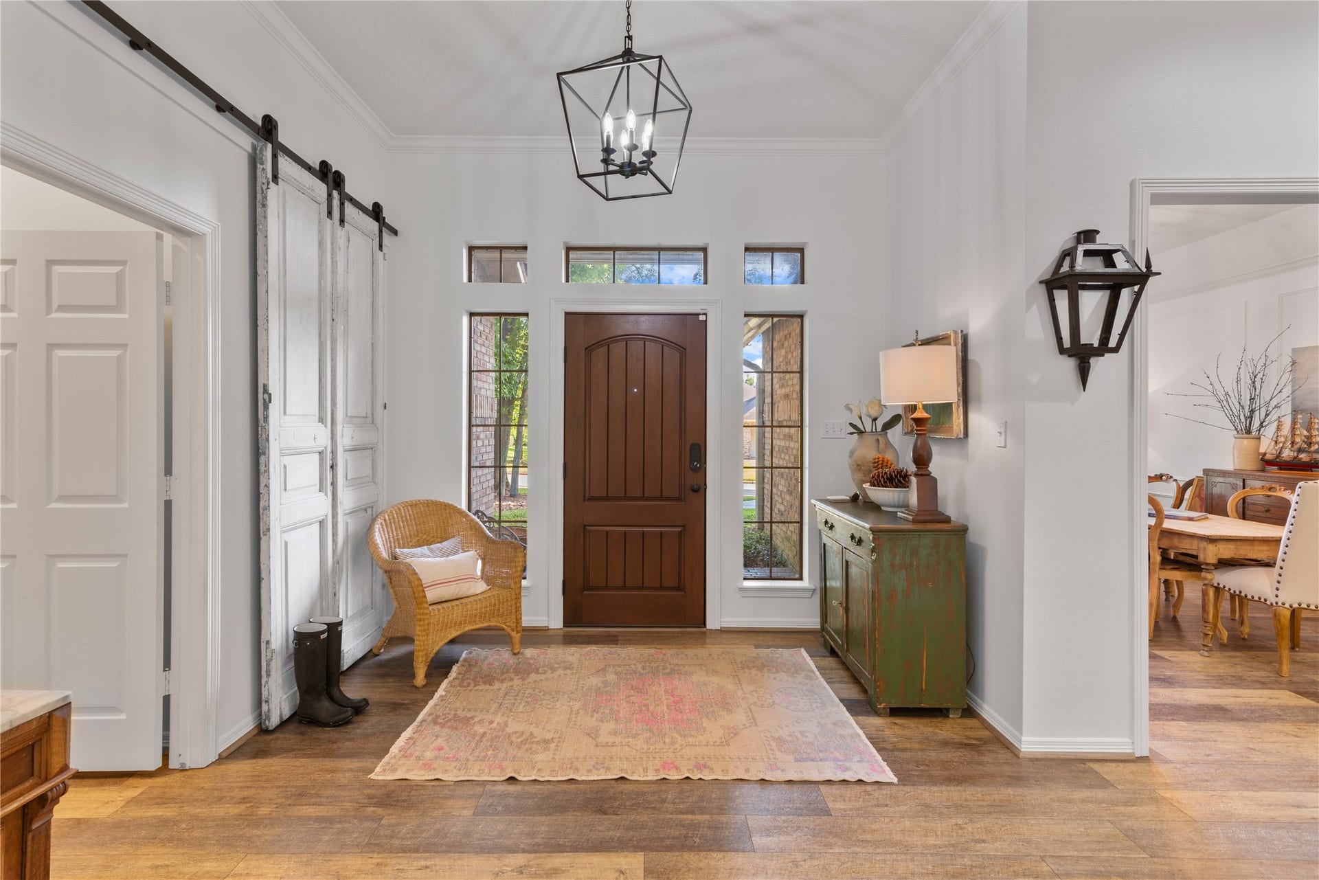 901 Longmire Road, #51, Conroe, TX 77304 Inviting entryway with warm wood accents, featuring a rustic barn door and elegant light fixtures. The space is complemented by a cozy wicker chair and a charming distressed console table.