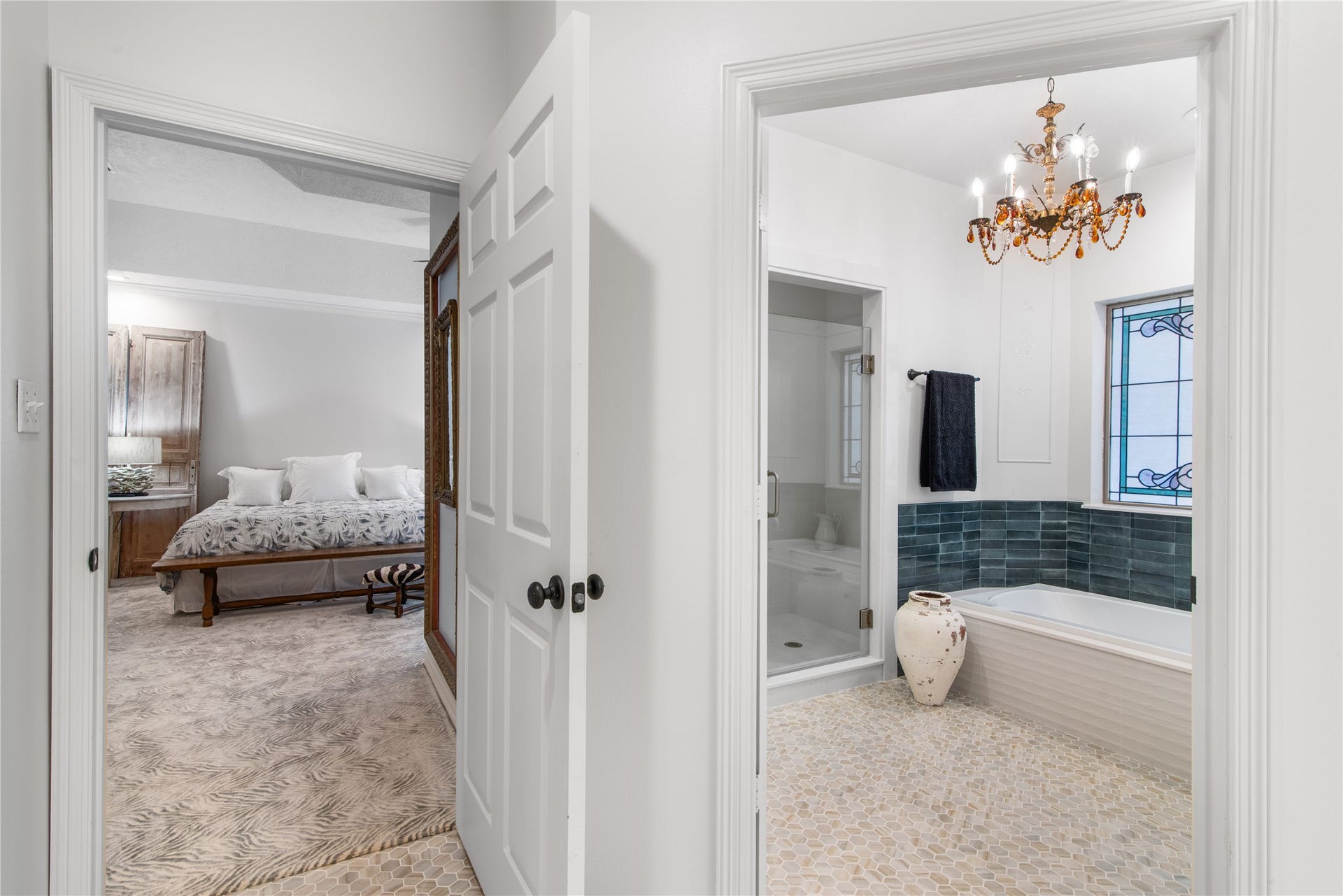 901 Longmire Road, #51, Conroe, TX 77304 Elegant bathroom featuring a luxurious soaking tub, glass-enclosed shower, and a stunning chandelier, seamlessly connected to a cozy bedroom with plush carpeting.