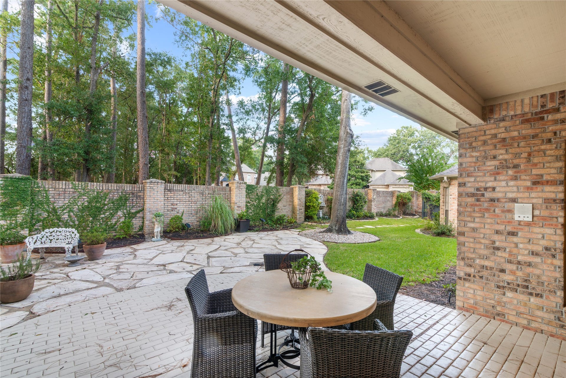 901 Longmire Road, #51, Conroe, TX 77304 Enjoy privacy with a brick wall and serene outdoor living with a spacious patio featuring elegant stone pathways, lush greenery.