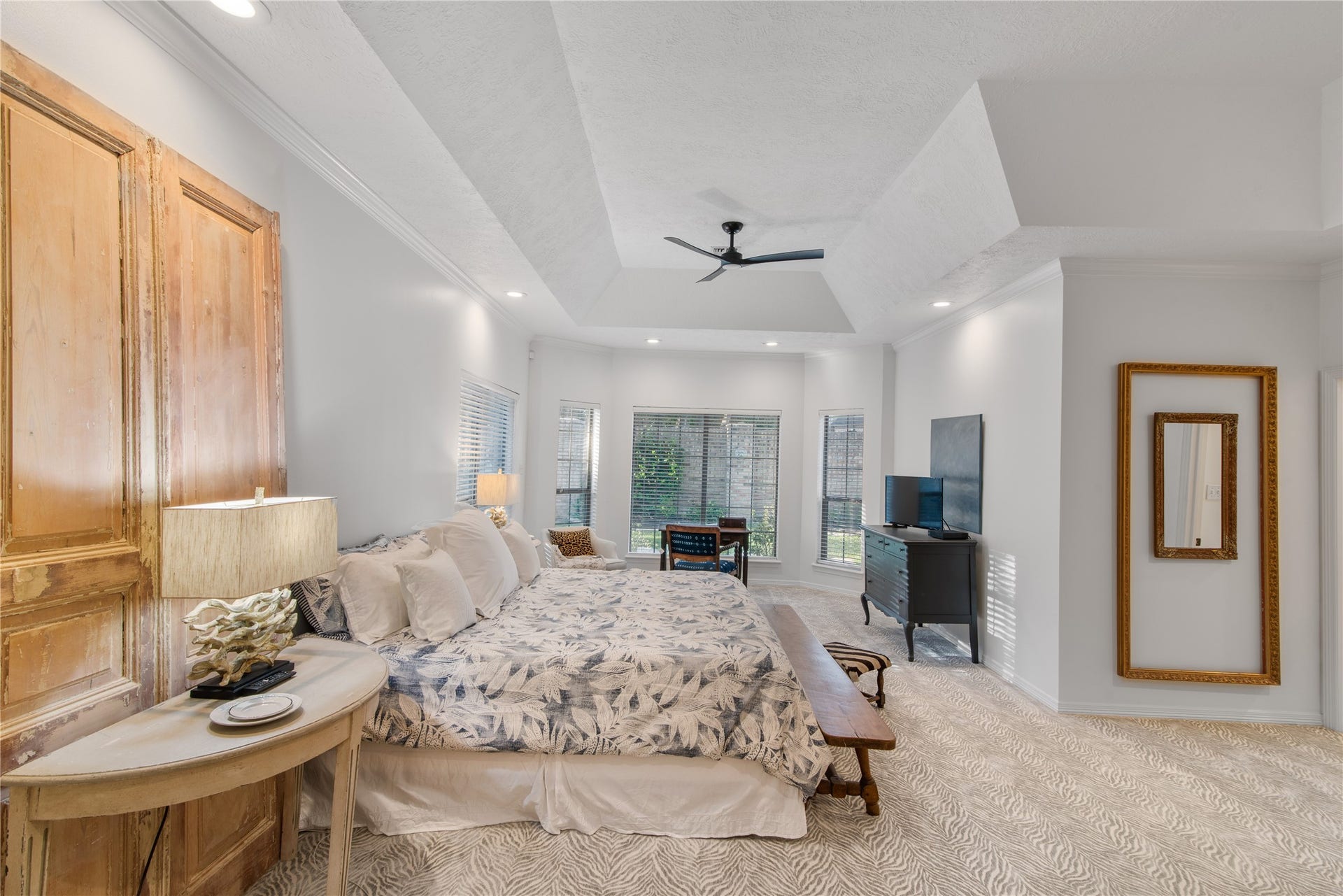 901 Longmire Road, #51, Conroe, TX 77304 Spacious bedroom with elegant tray ceiling, abundant natural light from large windows, and cozy carpet flooring.