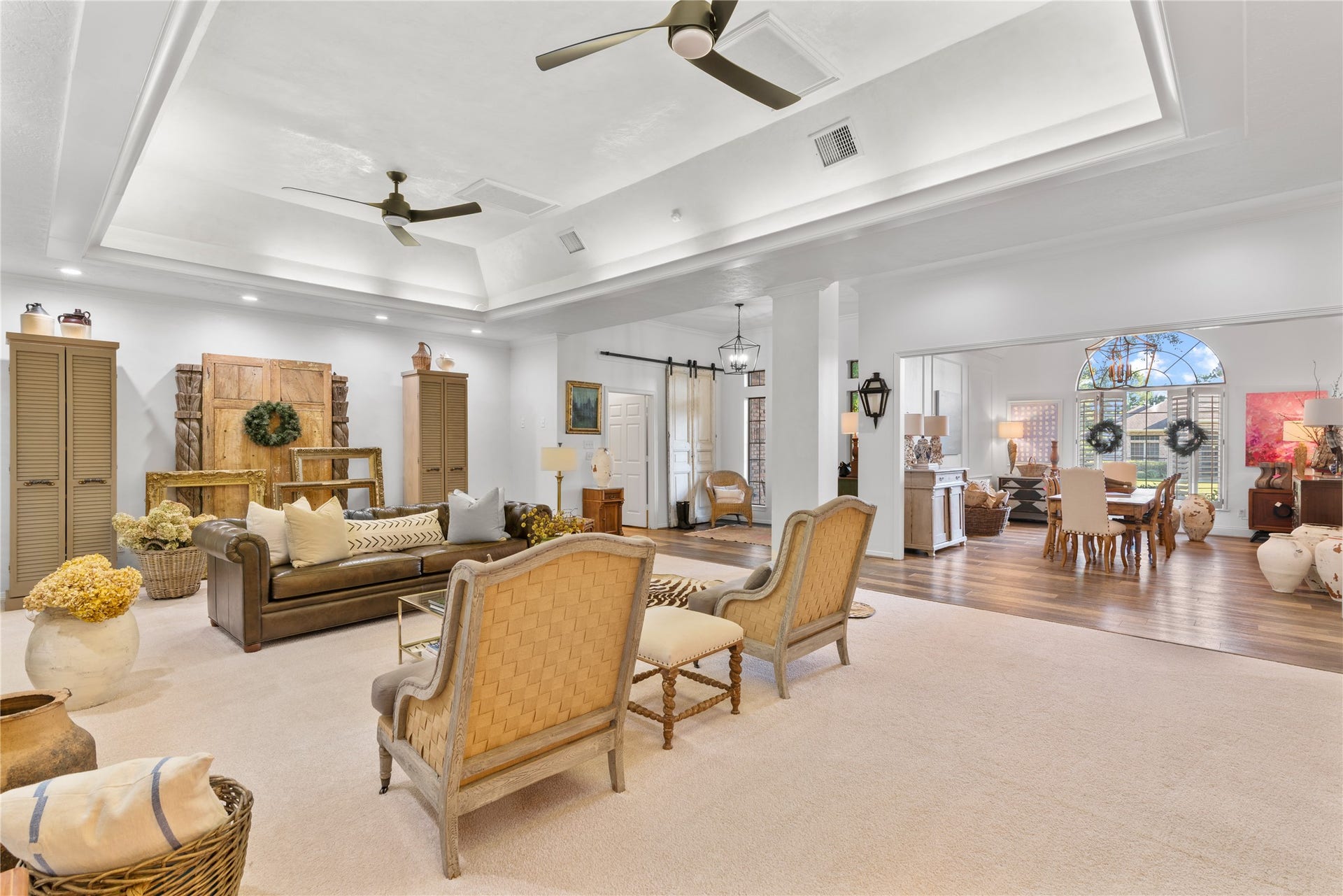 901 Longmire Road, #51, Conroe, TX 77304 Extra Large living area with elegant tray ceilings and dual ceiling fans, seamlessly flowing into a bright dining space with large arched windows, perfect for entertaining and relaxation. Walls are customized with plaster for a highend touch.