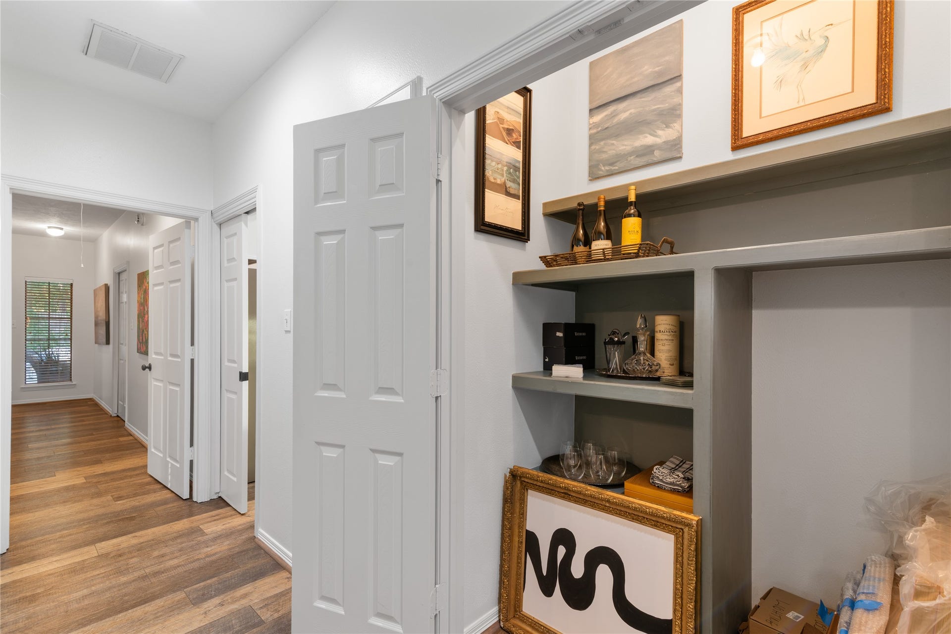 901 Longmire Road, #51, Conroe, TX 77304 Hallway with elegant wood flooring, built-in shelving adorned with tasteful decor, and a glimpse into a cozy, well-lit room.