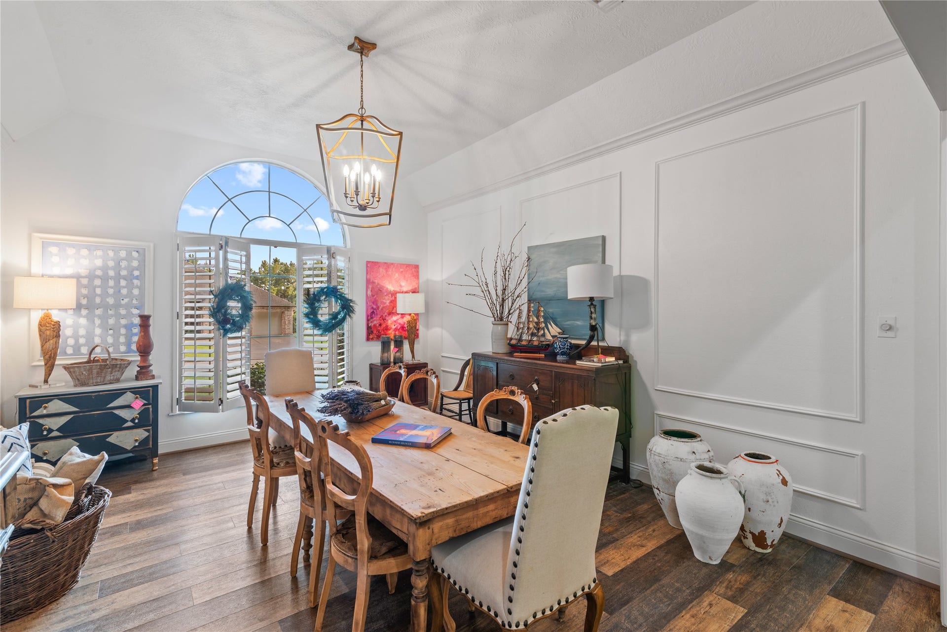 901 Longmire Road, #51, Conroe, TX 77304 Large arched window with plantation shutters, elegant wainscoting, and a rustic wooden table, complemented by stylish decor and a warm, inviting atmosphere in your formal dining area that opens to the living area and fireplace.