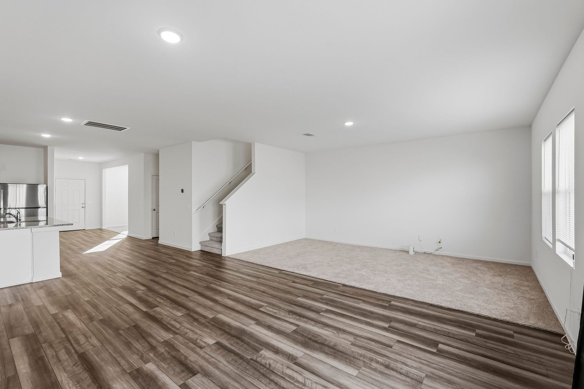 21547 Rolling Streams Drive, New Caney, TX 77357 Rich wood-look flooring flows throughout the main gathering space, beautifully contrasting with crisp white walls and recessed ceiling lighting.