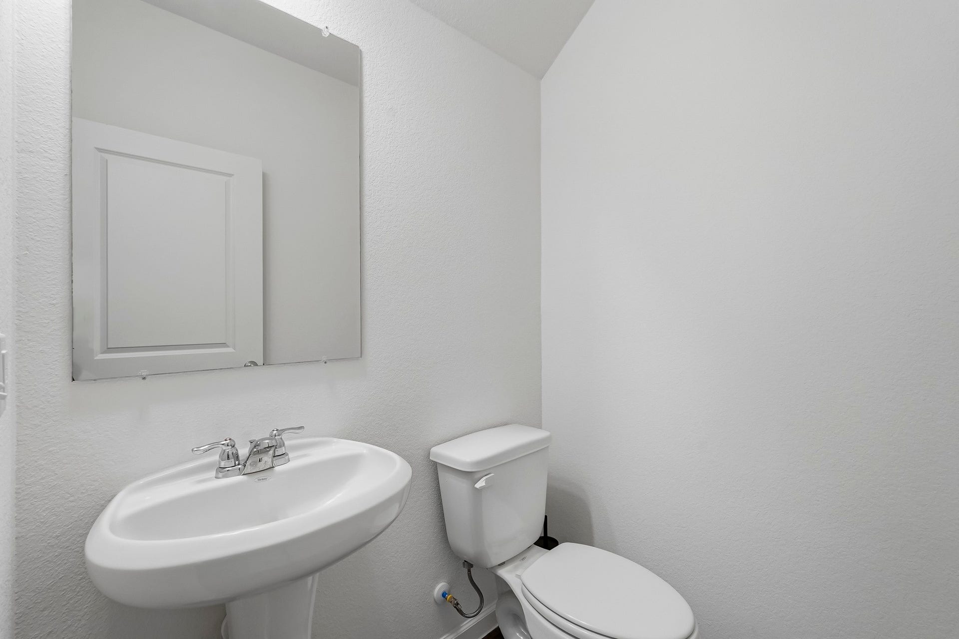 21547 Rolling Streams Drive, New Caney, TX 77357 This compact half bathroom features a clean, minimalist design with crisp white textured walls and a bright, neutral color palette.