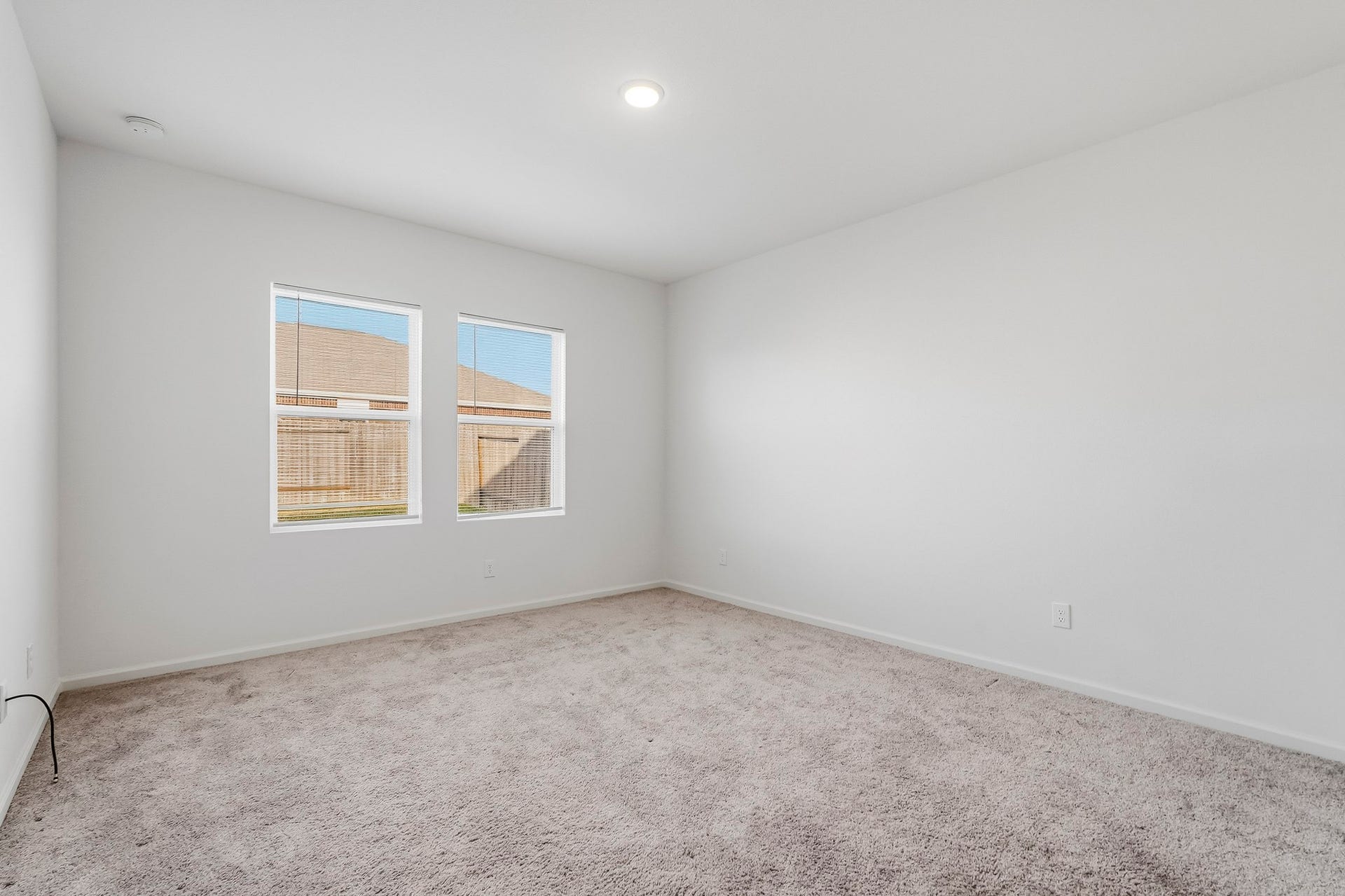 21547 Rolling Streams Drive, New Caney, TX 77357 This spacious master bedroom features a bright, open layout with crisp white walls, soft neutral carpeting, and a clean, modern aesthetic. Two generously sized windows allow natural light to fill the room, creating an airy and welcoming atmosphere. The high ceiling and recessed lighting enhance the sense of openness, while the expansive floor space offers flexibility for a variety of bedroom arrangements.